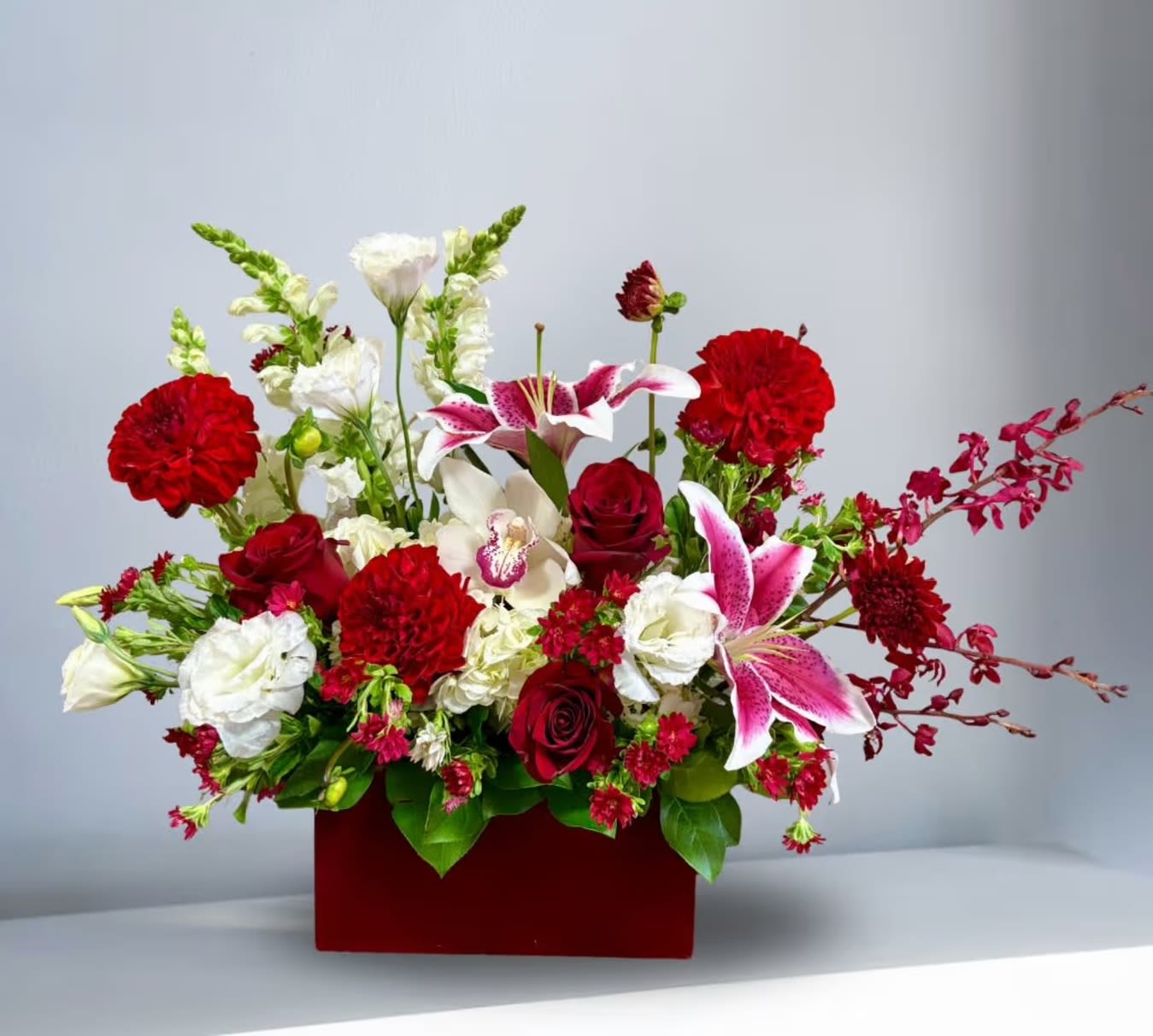 Mixed bouquet of red, white, and pink flowers in a red box