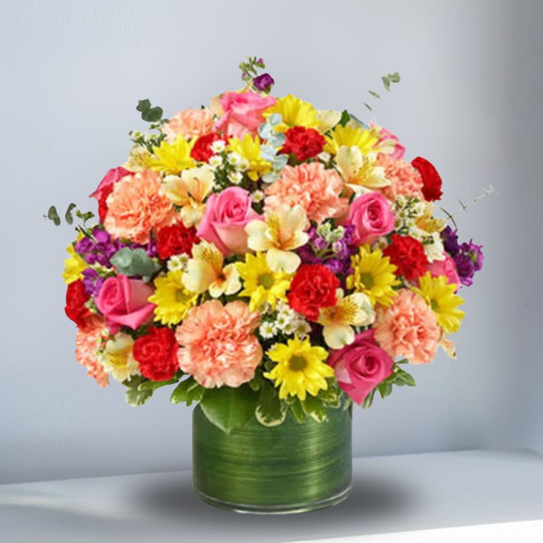 Mixed bouquet of pink, yellow, red, and peach flowers in a green vase