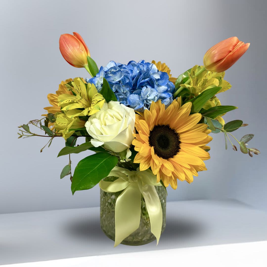 California Coastal Sunshine - California Coast Sunshine! Perfect for anyone who loves sunflowers and the coast! This caming arrangement includes sunflwers, hydrangae, roses, alstromeria, and tulips in a clear vase.