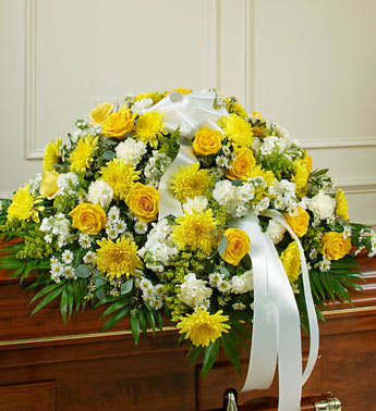 Yellow and white funeral spray with roses and chrysanthemums on a casket