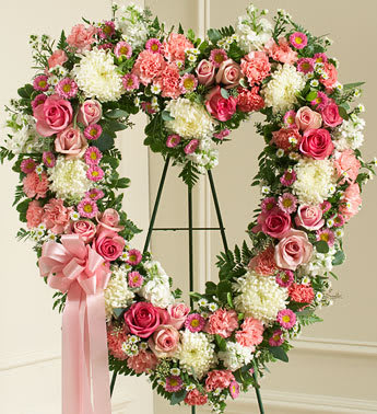 Heart-shaped floral wreath with pink roses and white blooms on an easel