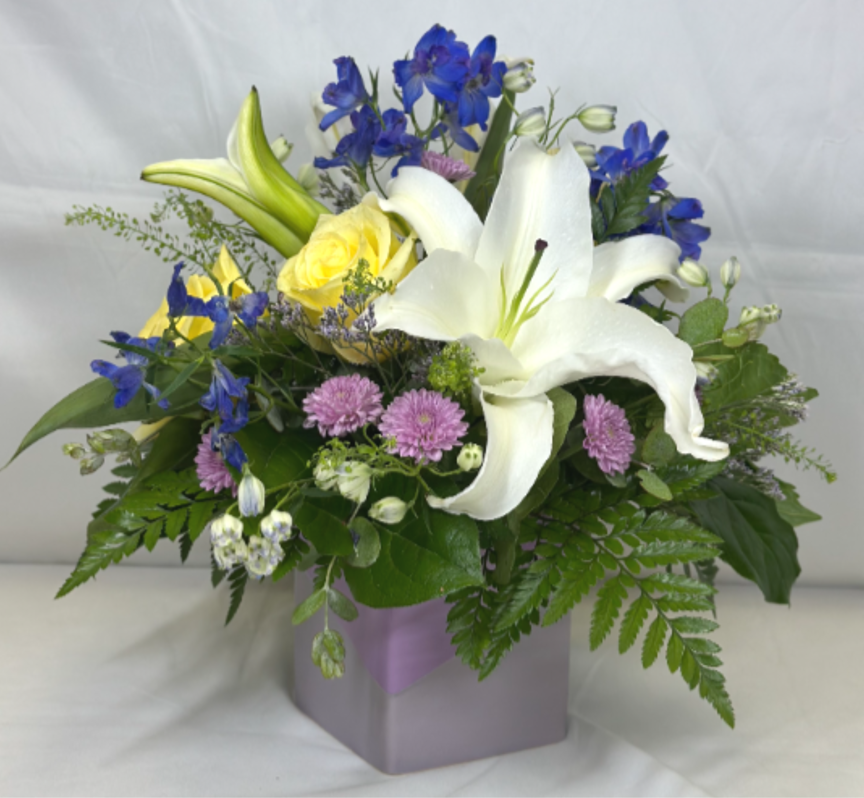 Morning Light - Just  daybreak there is a view of deep indigo and lavender among white clouds with the down of a yellow sun. That is the inspiration behind this Leary's Flowers exclusive design. If the featured flowers are unavailable we will design your arrangement using the freshest blooms of equal or greater value.