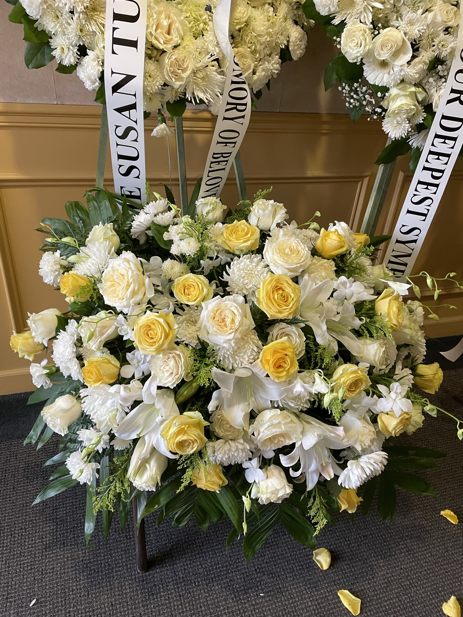 White and yellow funeral wreaths with memorial ribbons