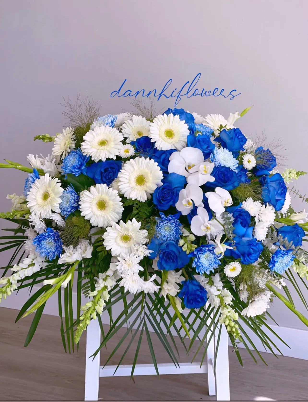 Blue and white floral spray with roses, daisies, and orchids