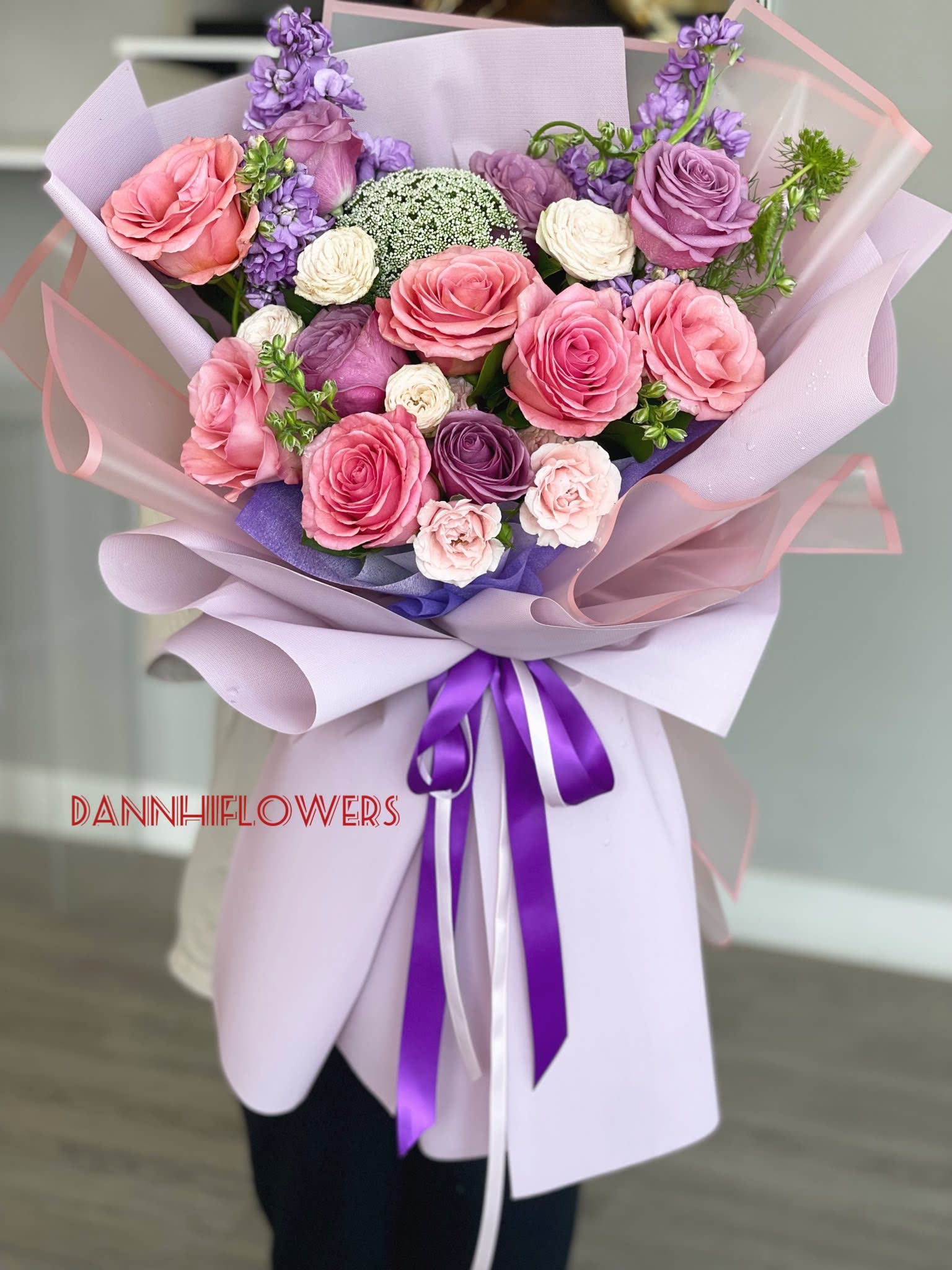 Hand-tied bouquet of pink and purple roses wrapped in lavender paper