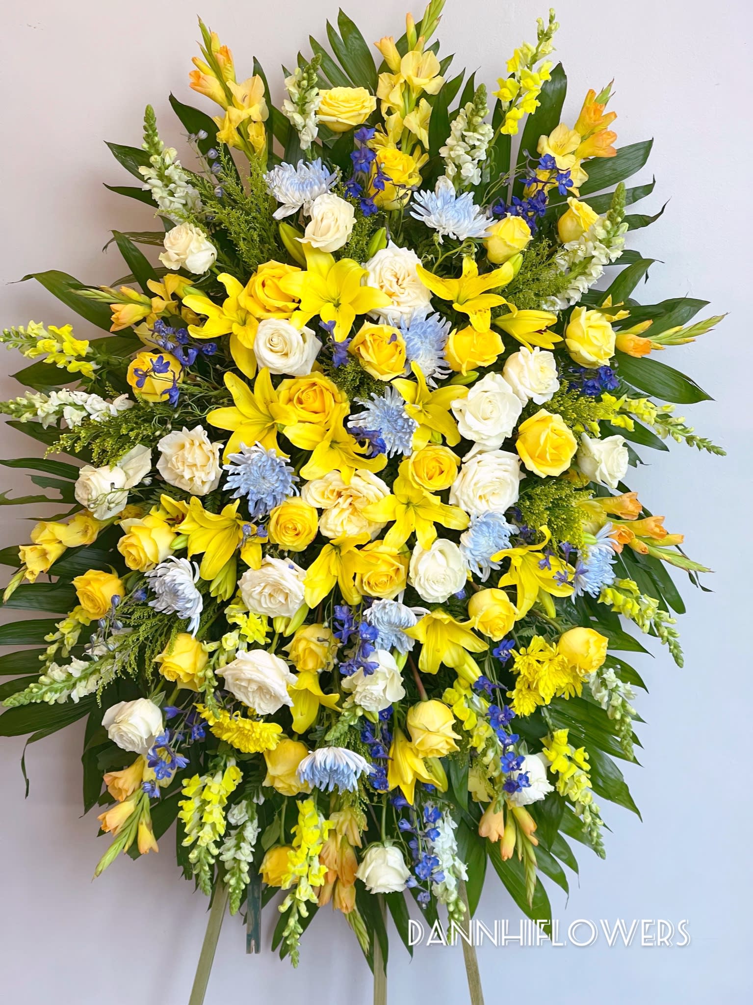 Large standing spray of yellow, white, and blue flowers