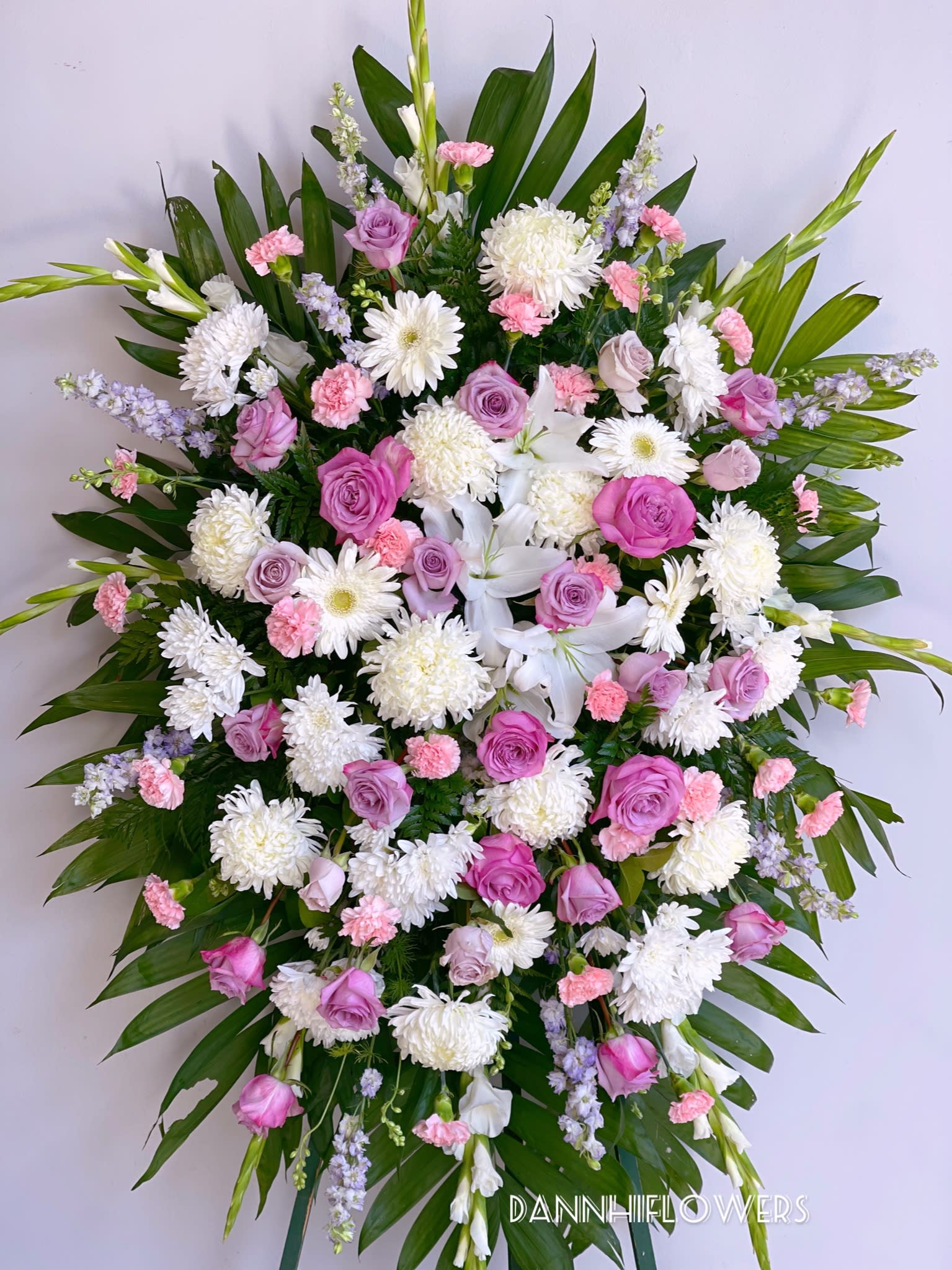 Large standing spray of pink and white flowers with palm leaves