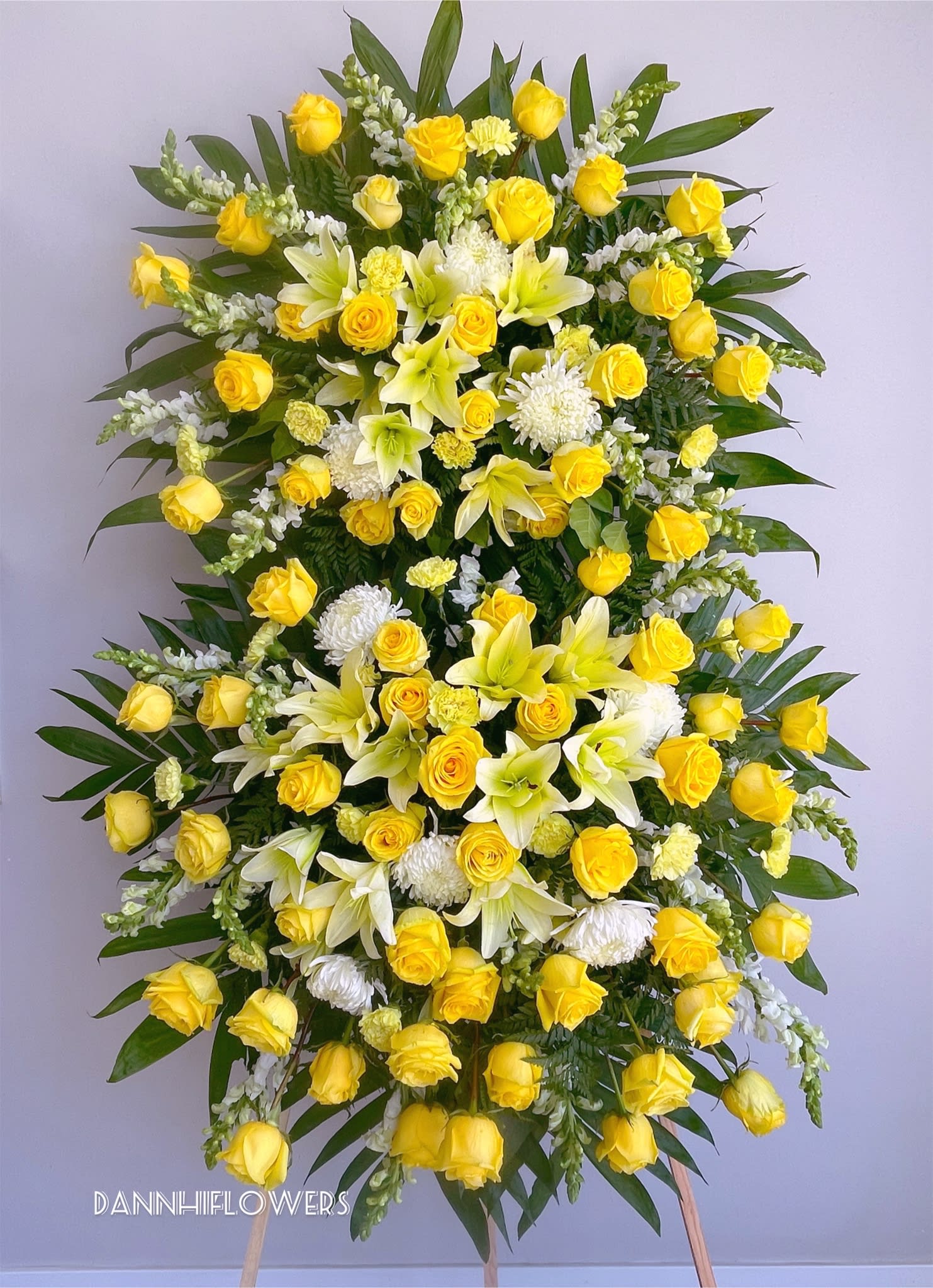 Standing floral spray with yellow roses, white lilies, and white mums