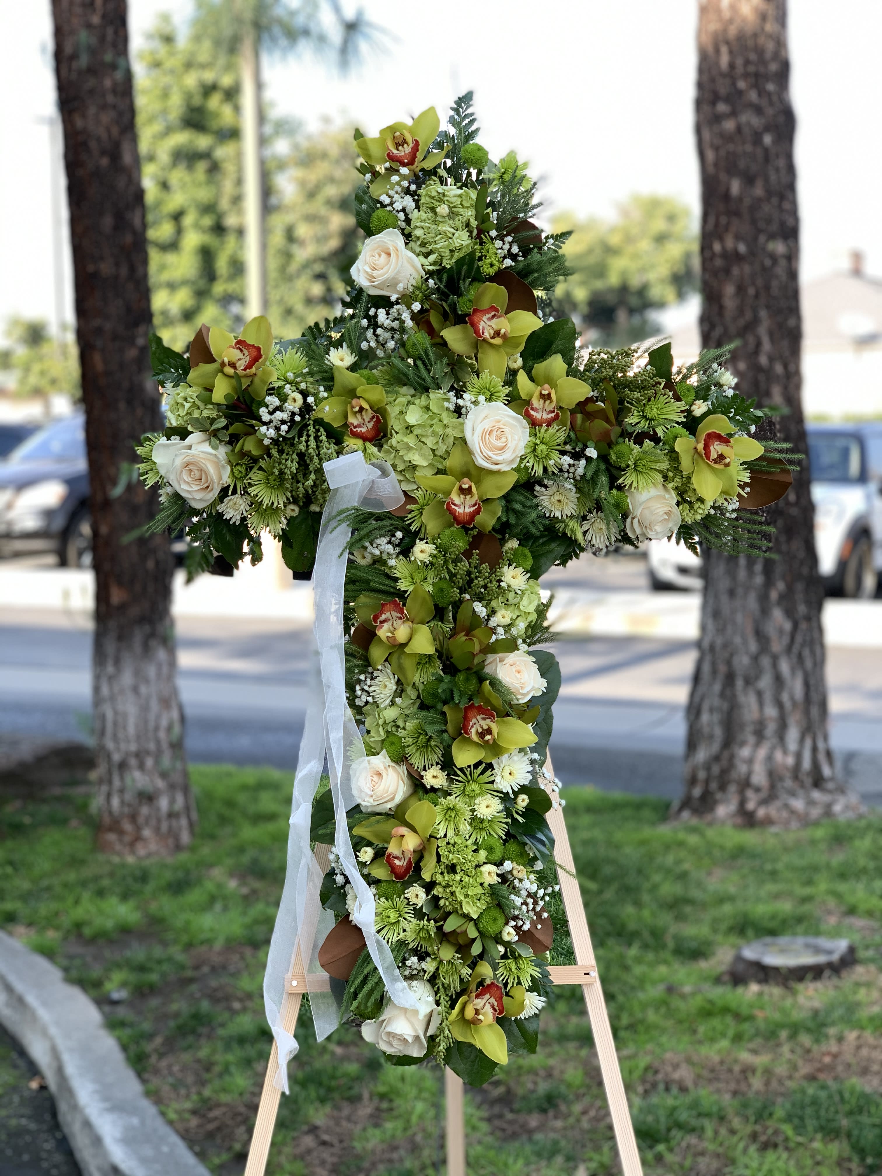 Large floral cross arrangement with white roses and green orchids