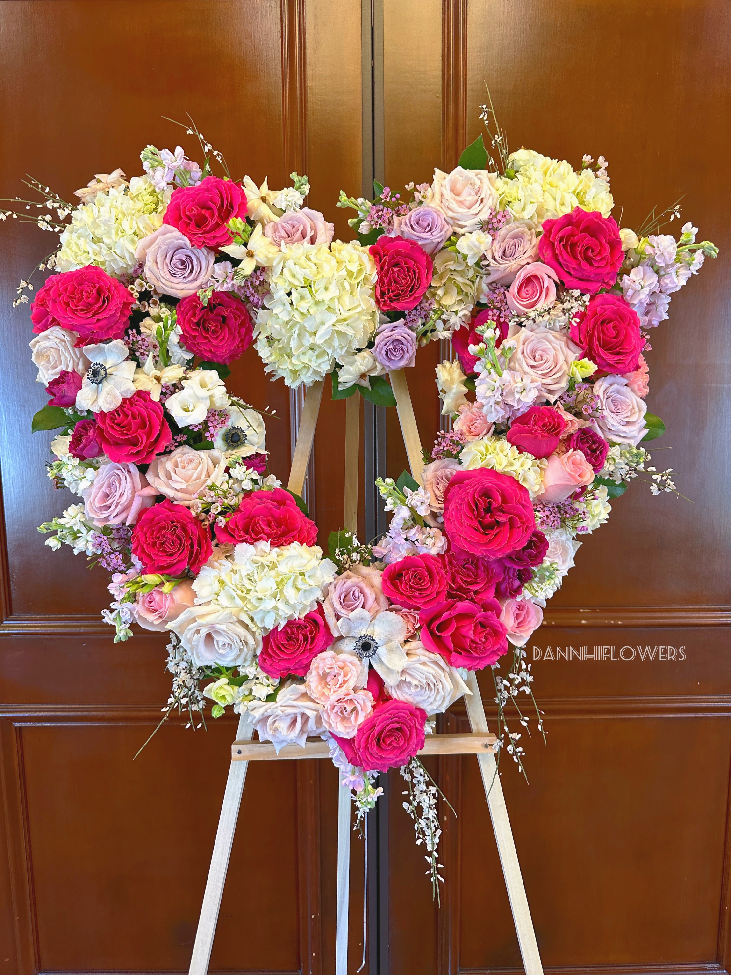 Heart-shaped floral arrangement of pink and cream roses on an easel