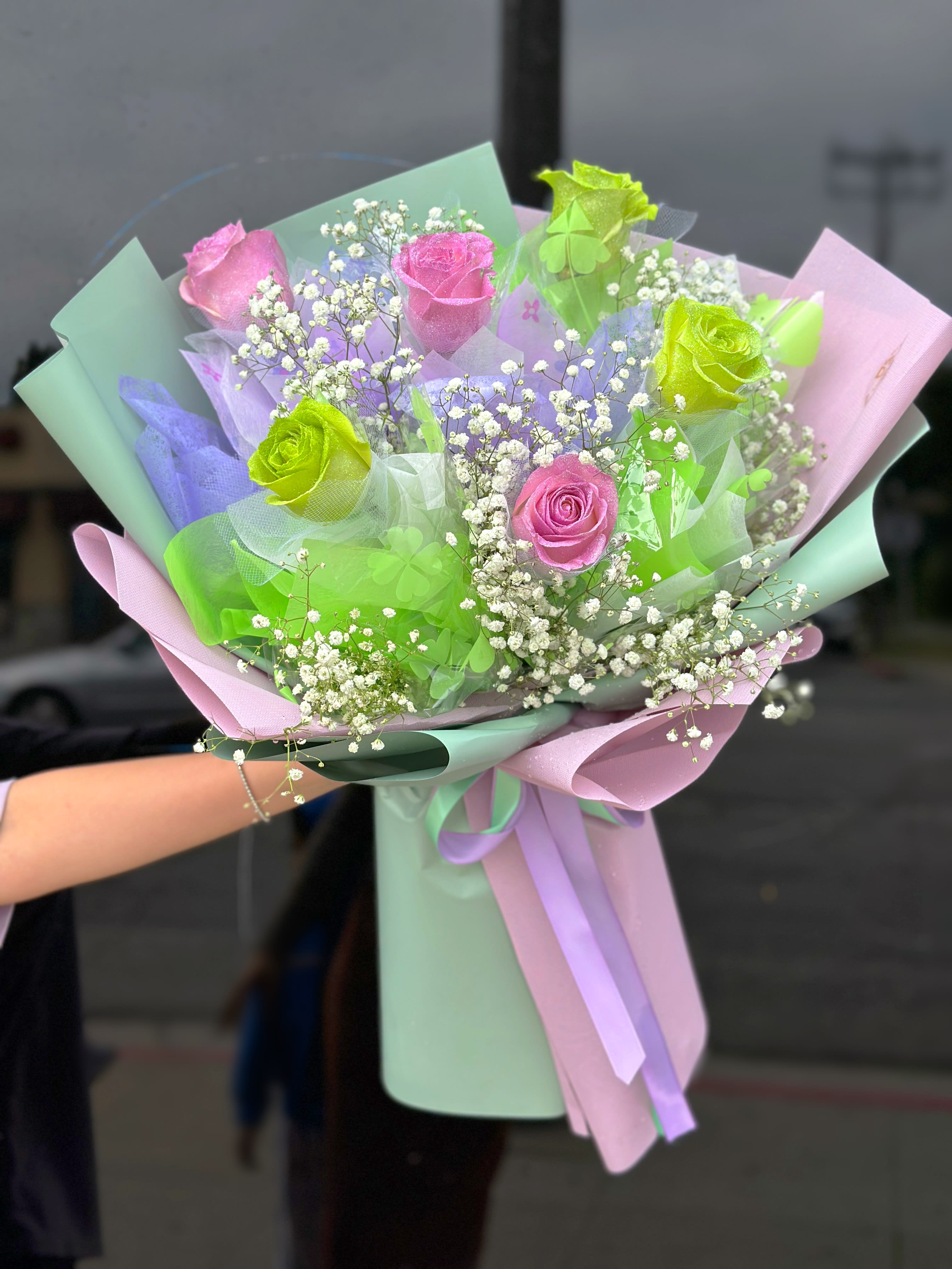 Bouquet of pink and green roses with baby's breath in pastel wrapping