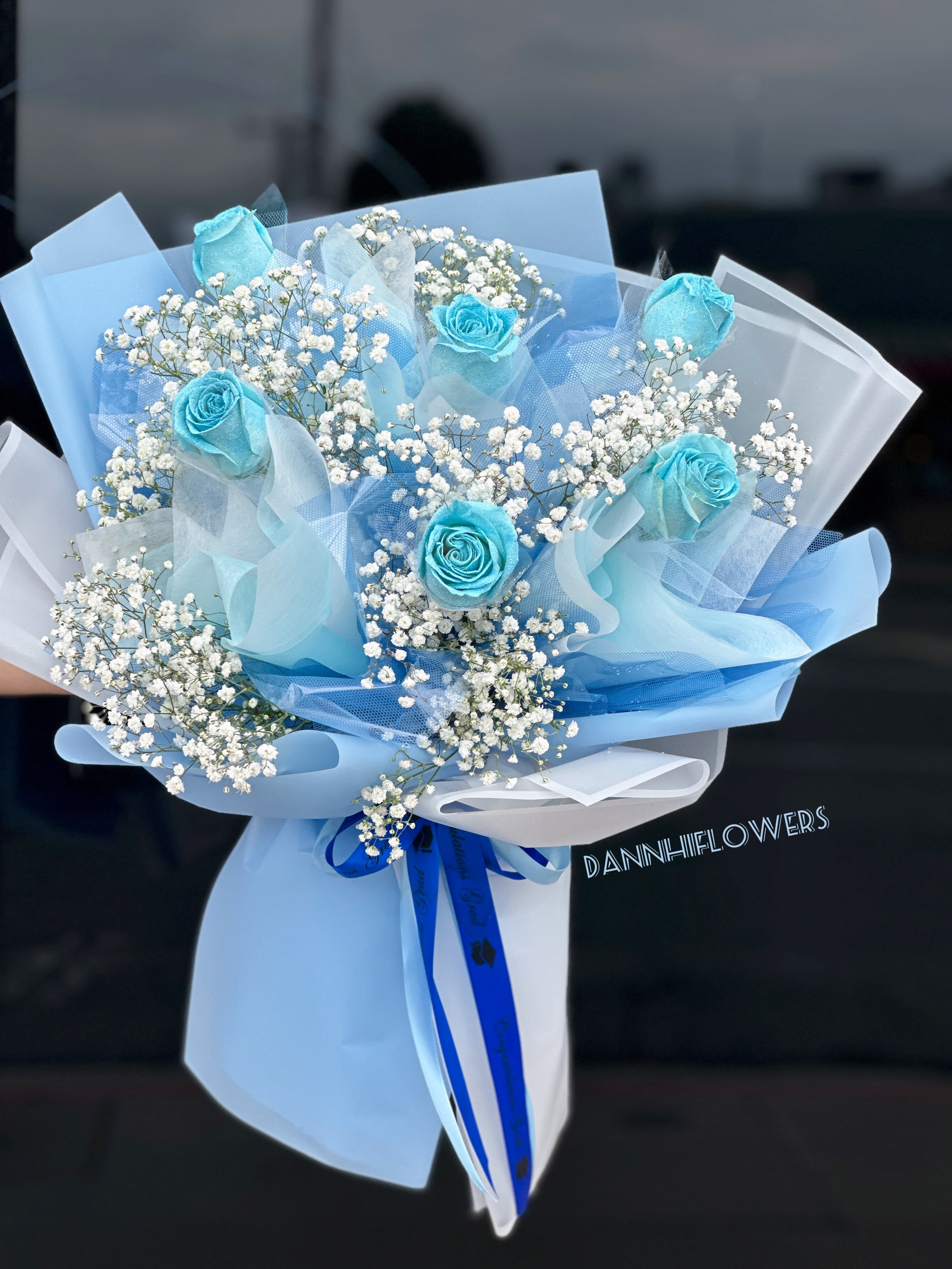 Bouquet of blue roses and white baby's breath wrapped in pale blue paper