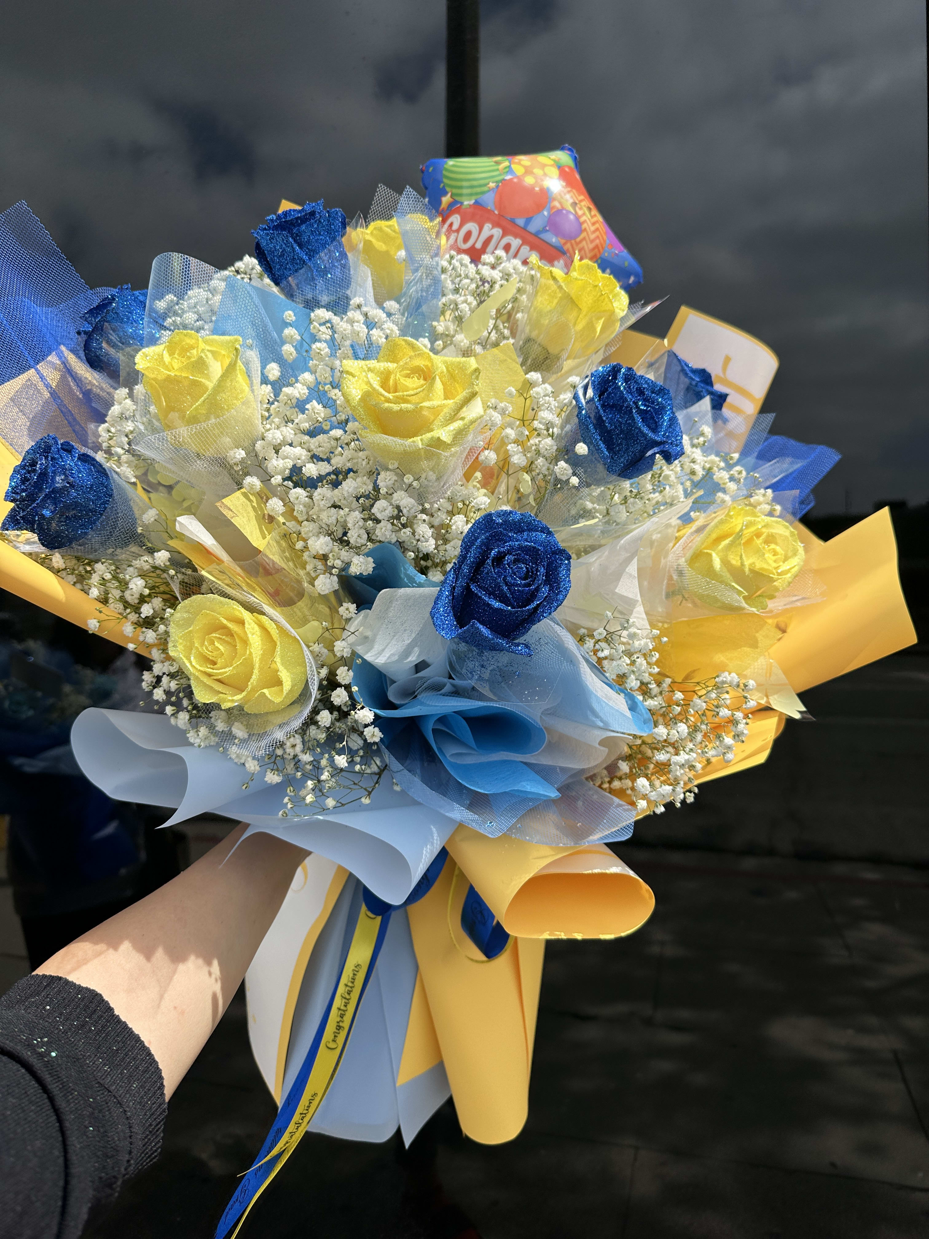 Bouquet of blue and yellow roses with baby's breath and colorful wrapping