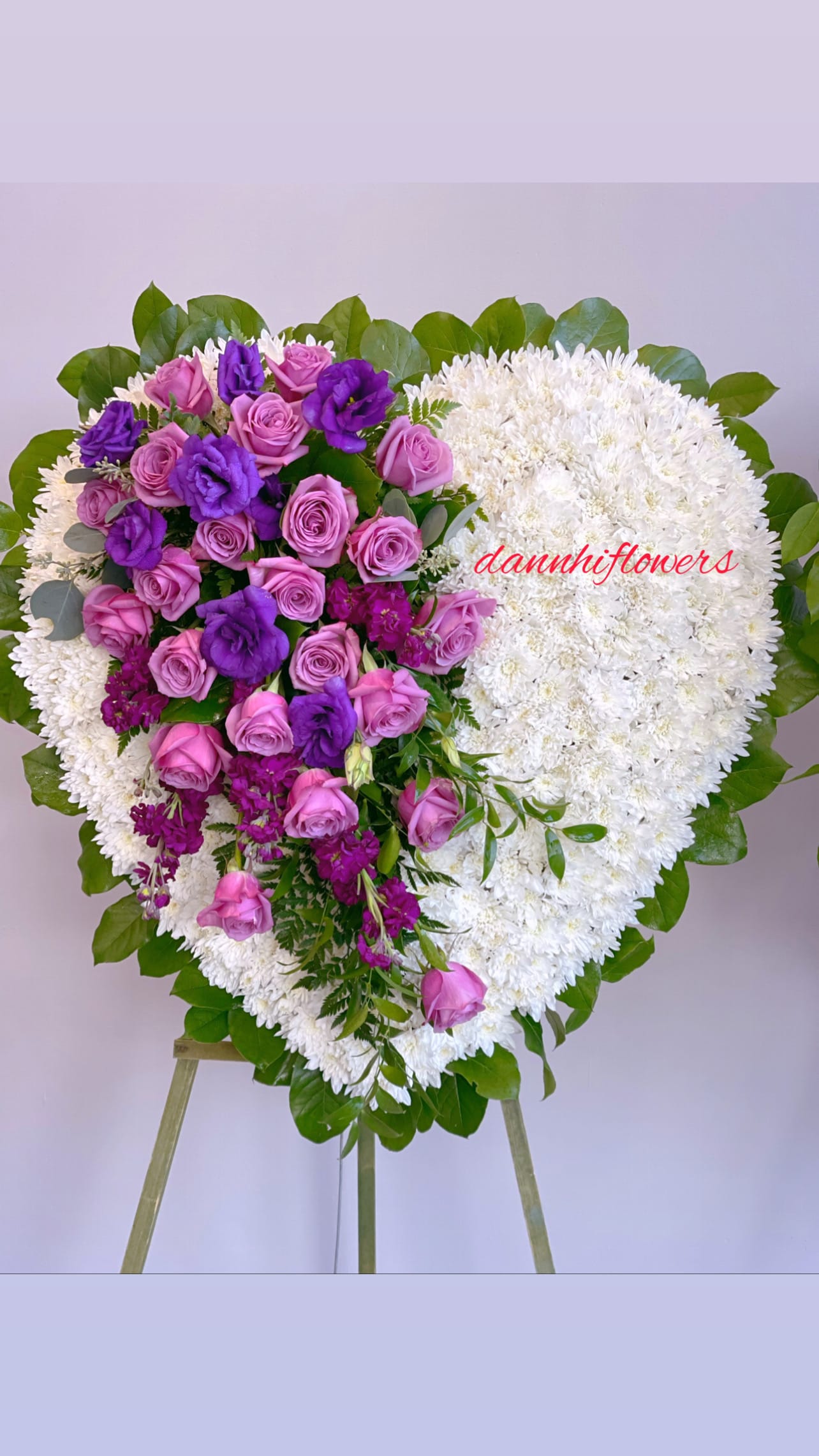 Heart-shaped floral wreath with pink and purple roses on white blooms