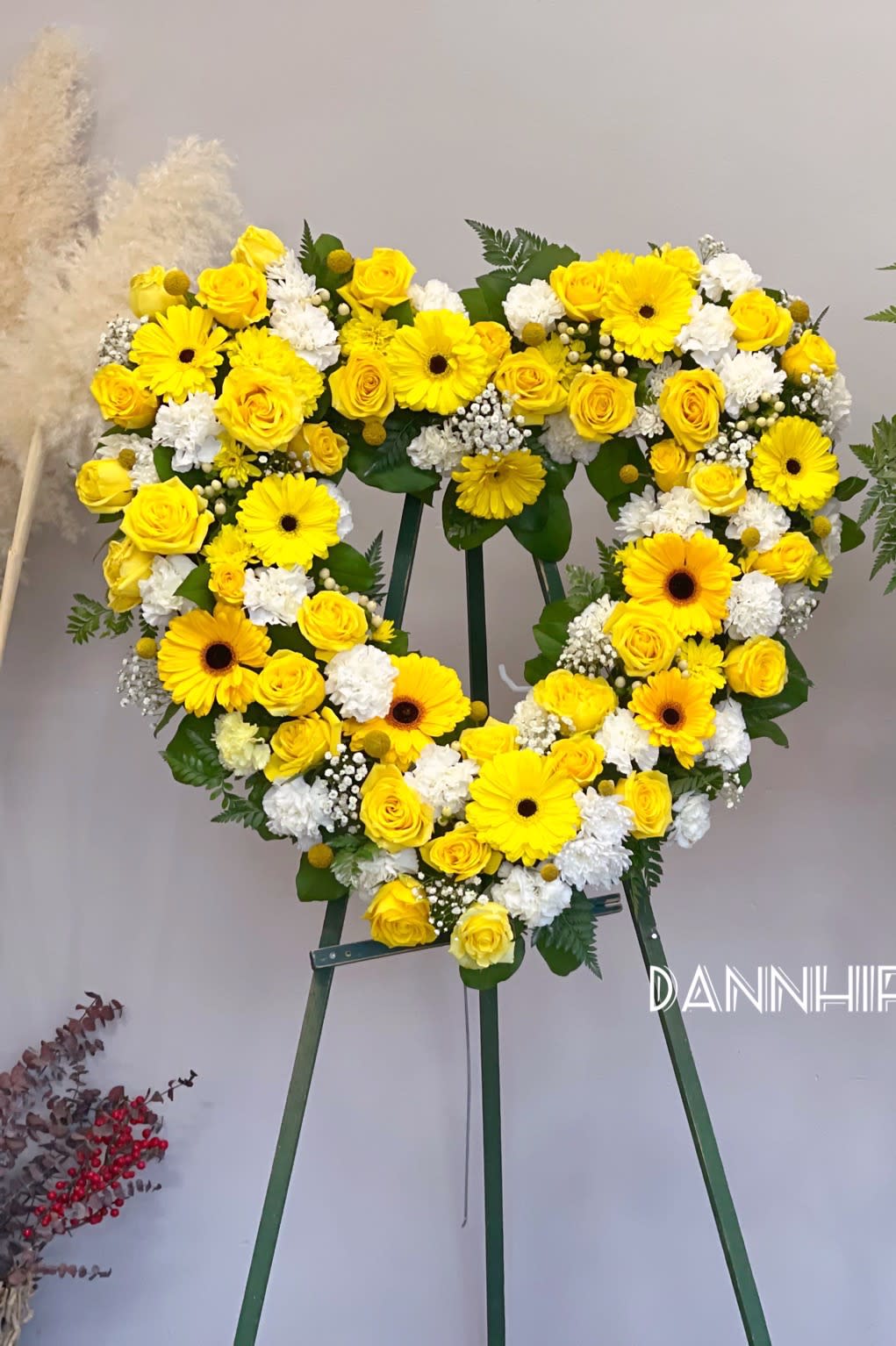 Yellow floral heart wreath on a stand with roses and daisies