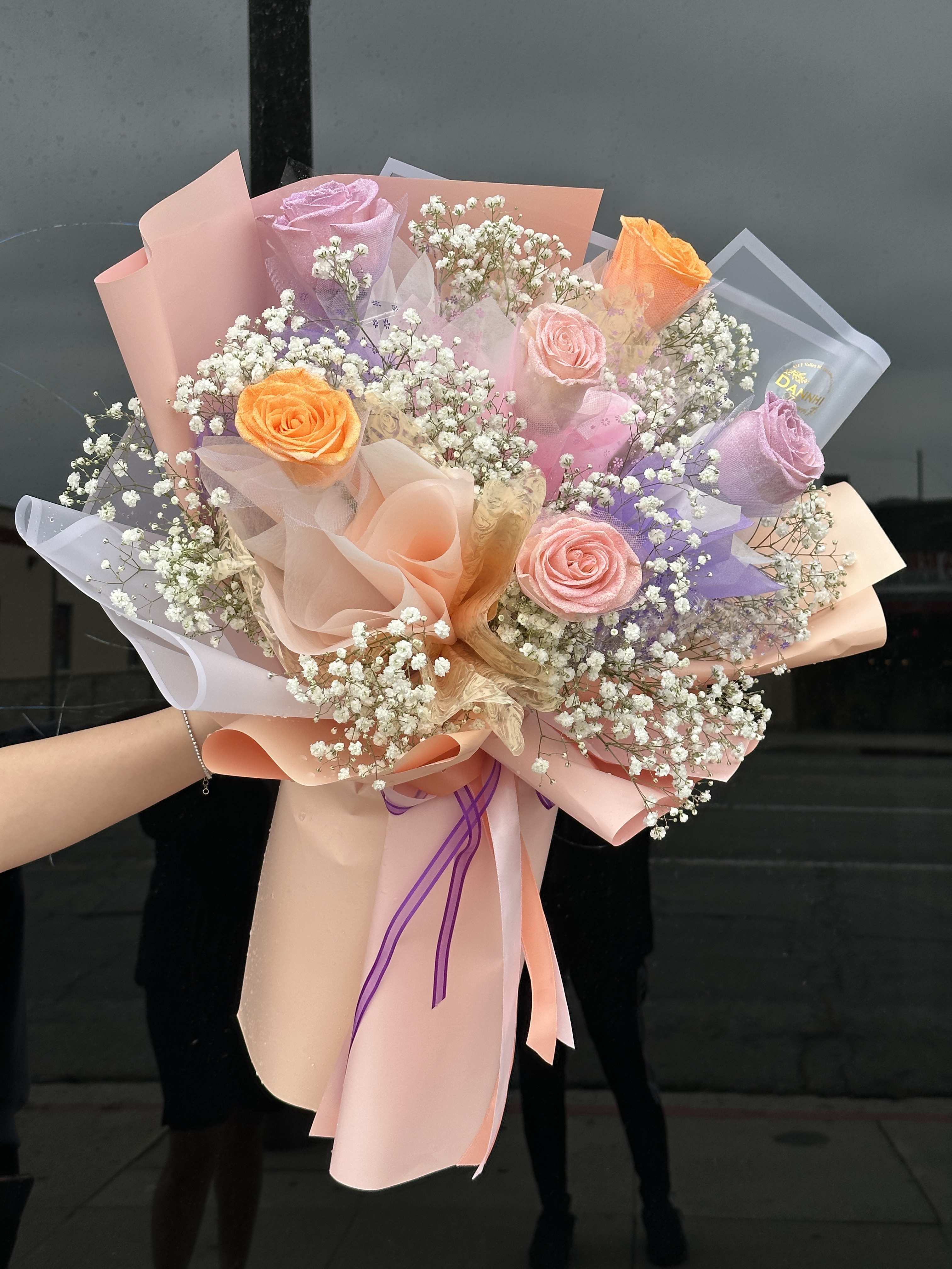 Bouquet of pastel roses and baby's breath wrapped in pink paper