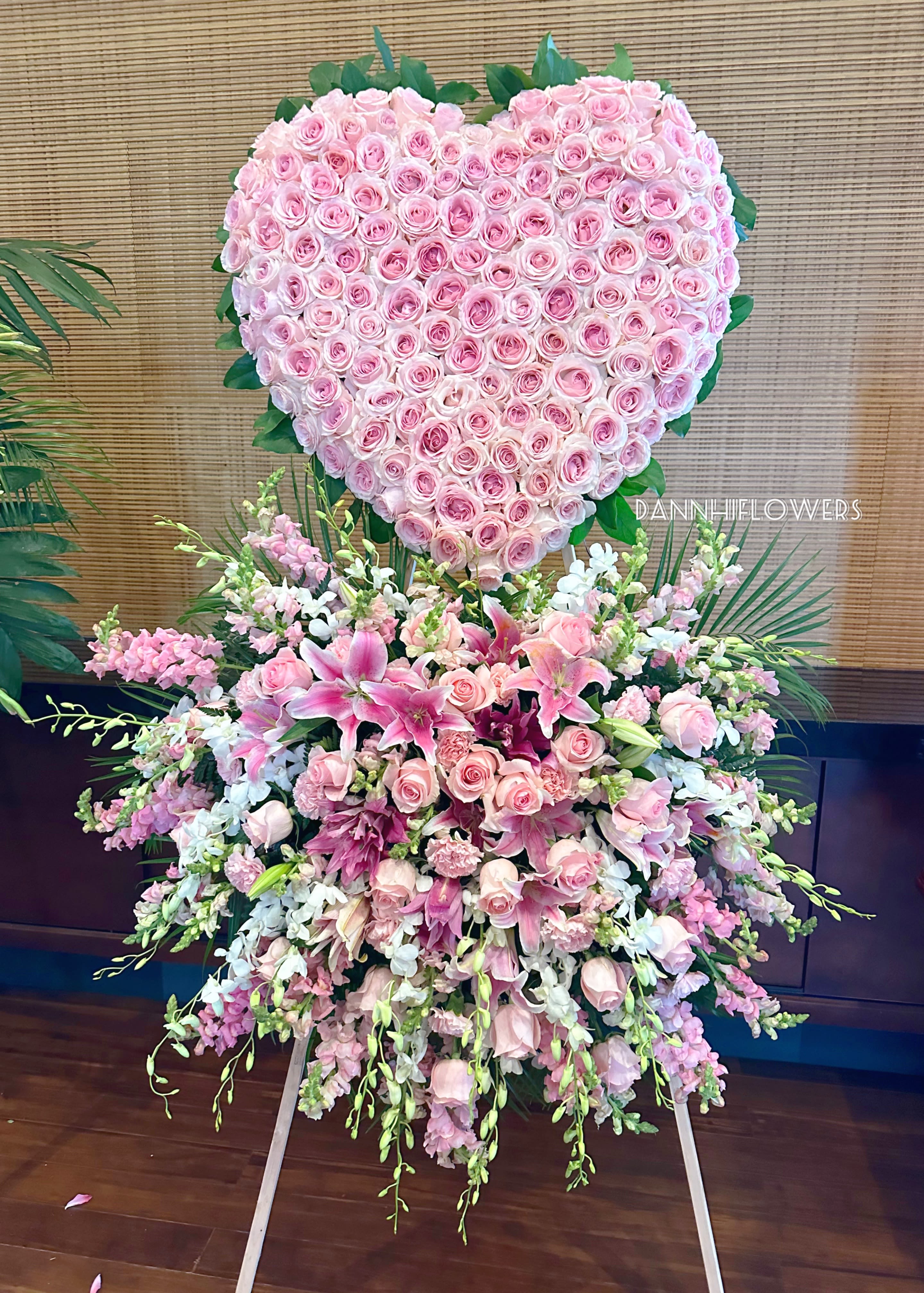 Heart-shaped pink rose arrangement above a cascading pink lily bouquet