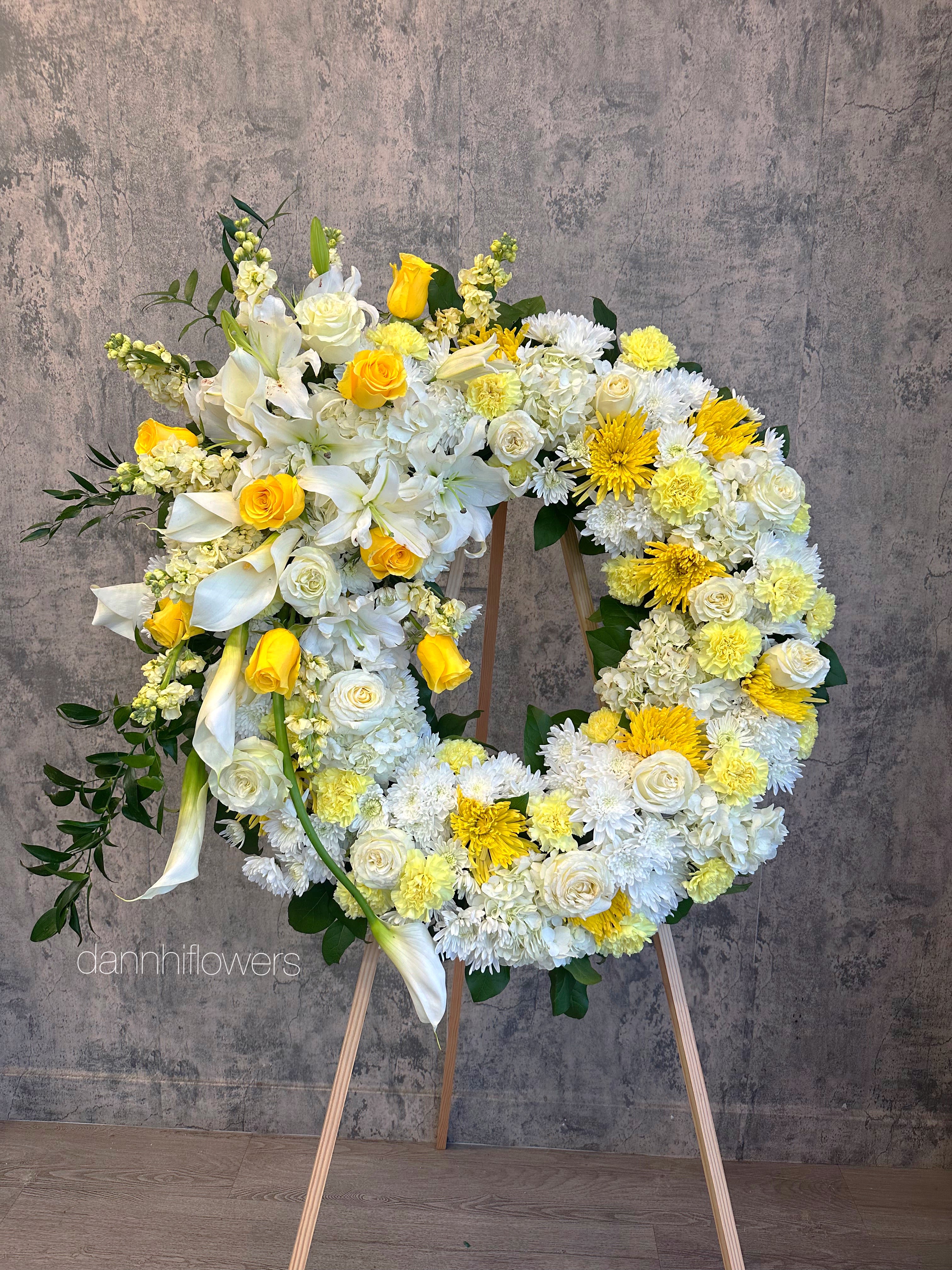 Large floral wreath on an easel with white and yellow flowers