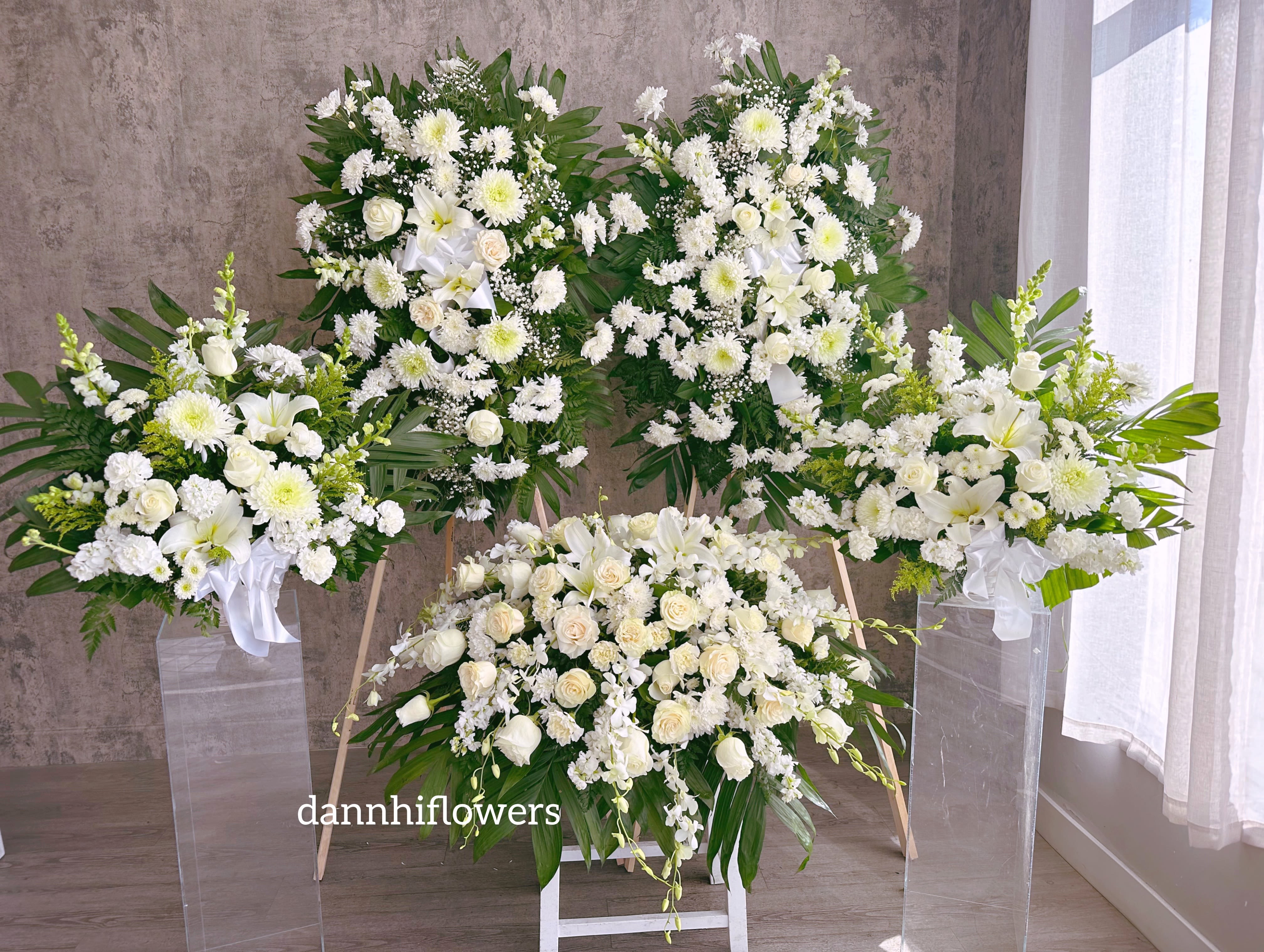 White floral funeral sprays and a casket spray with lilies and roses