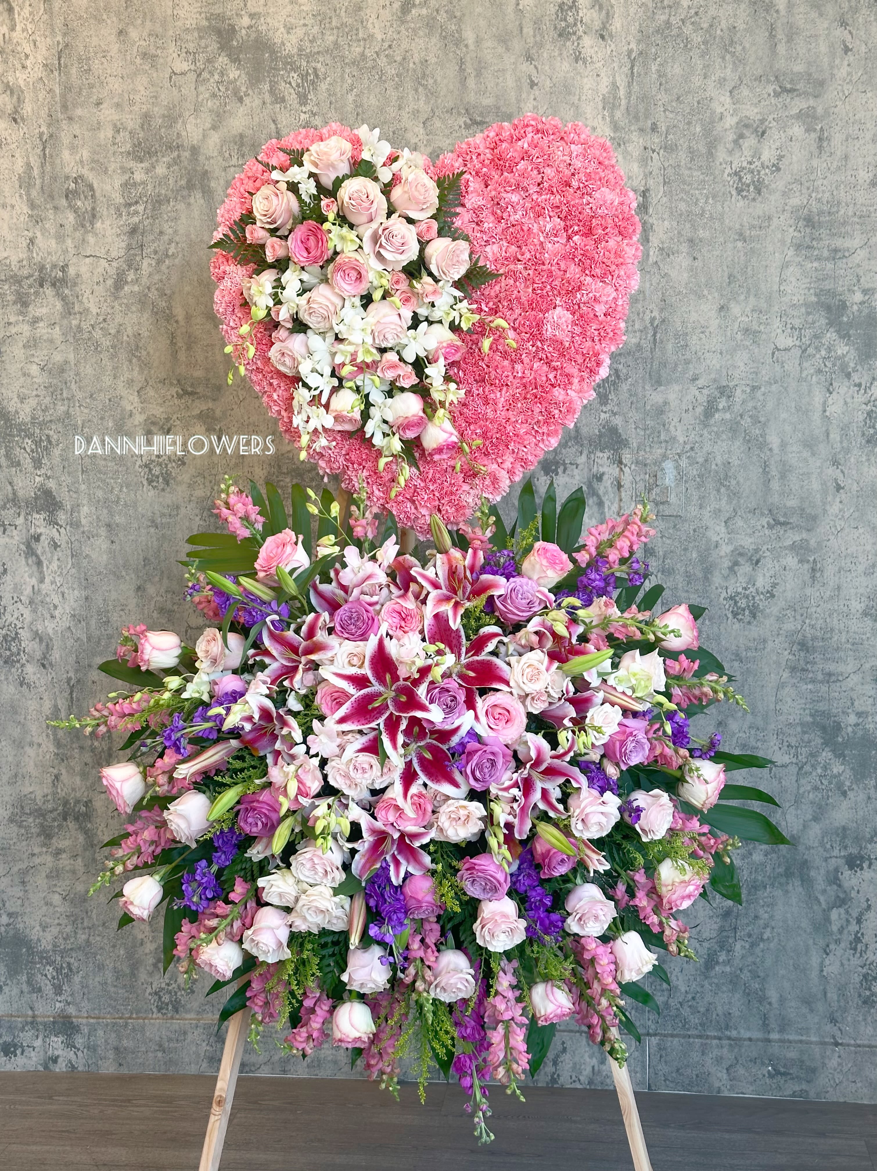 Large heart-shaped floral tribute with pink and white flowers on an easel