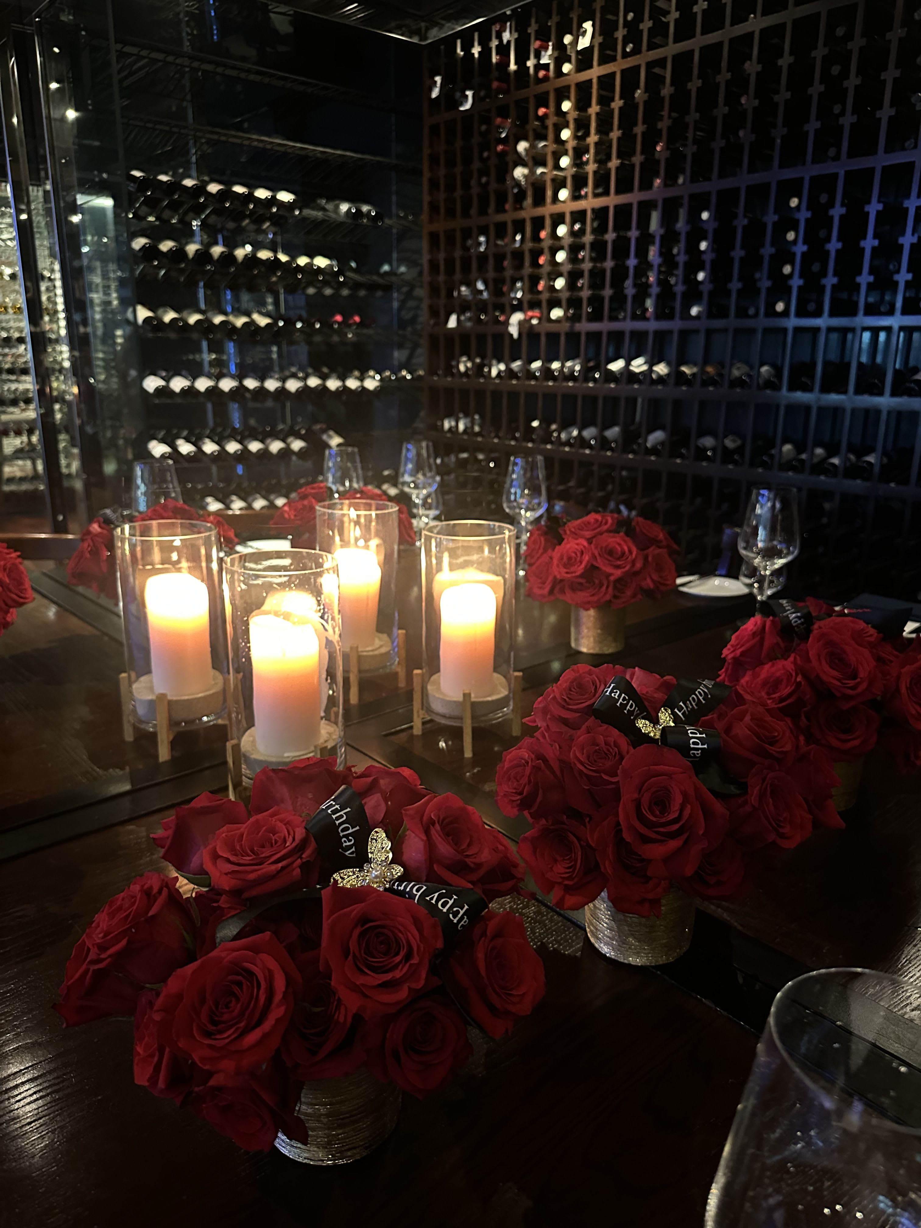 Red rose centerpieces with lit candles on a dining table