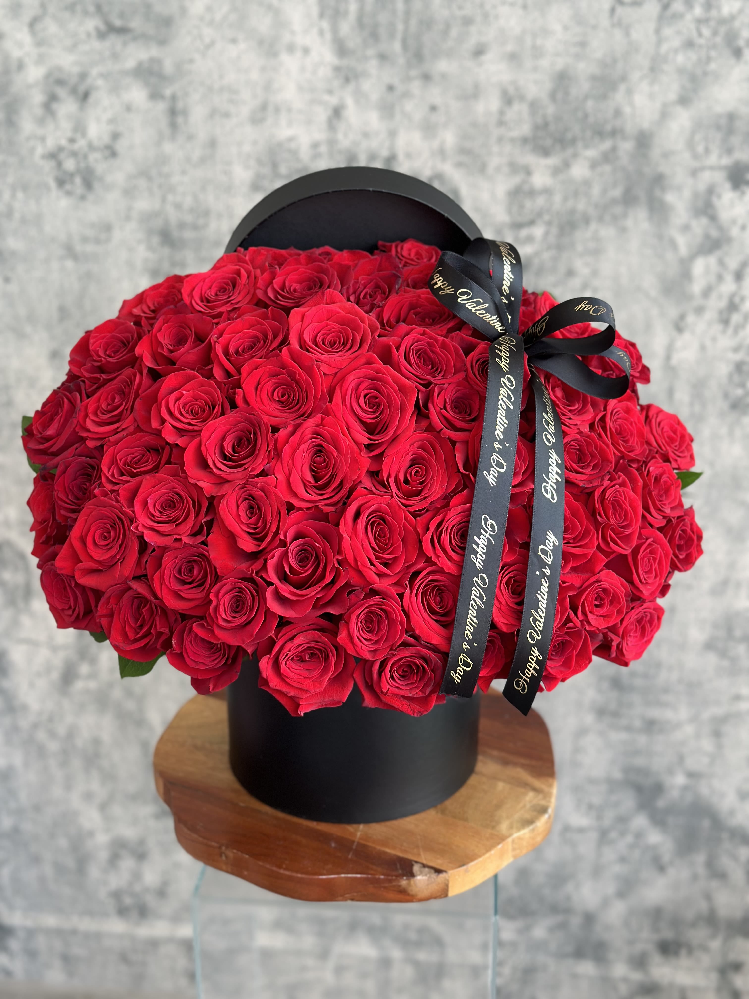 Large bouquet of red roses in a black hat box with a ribbon