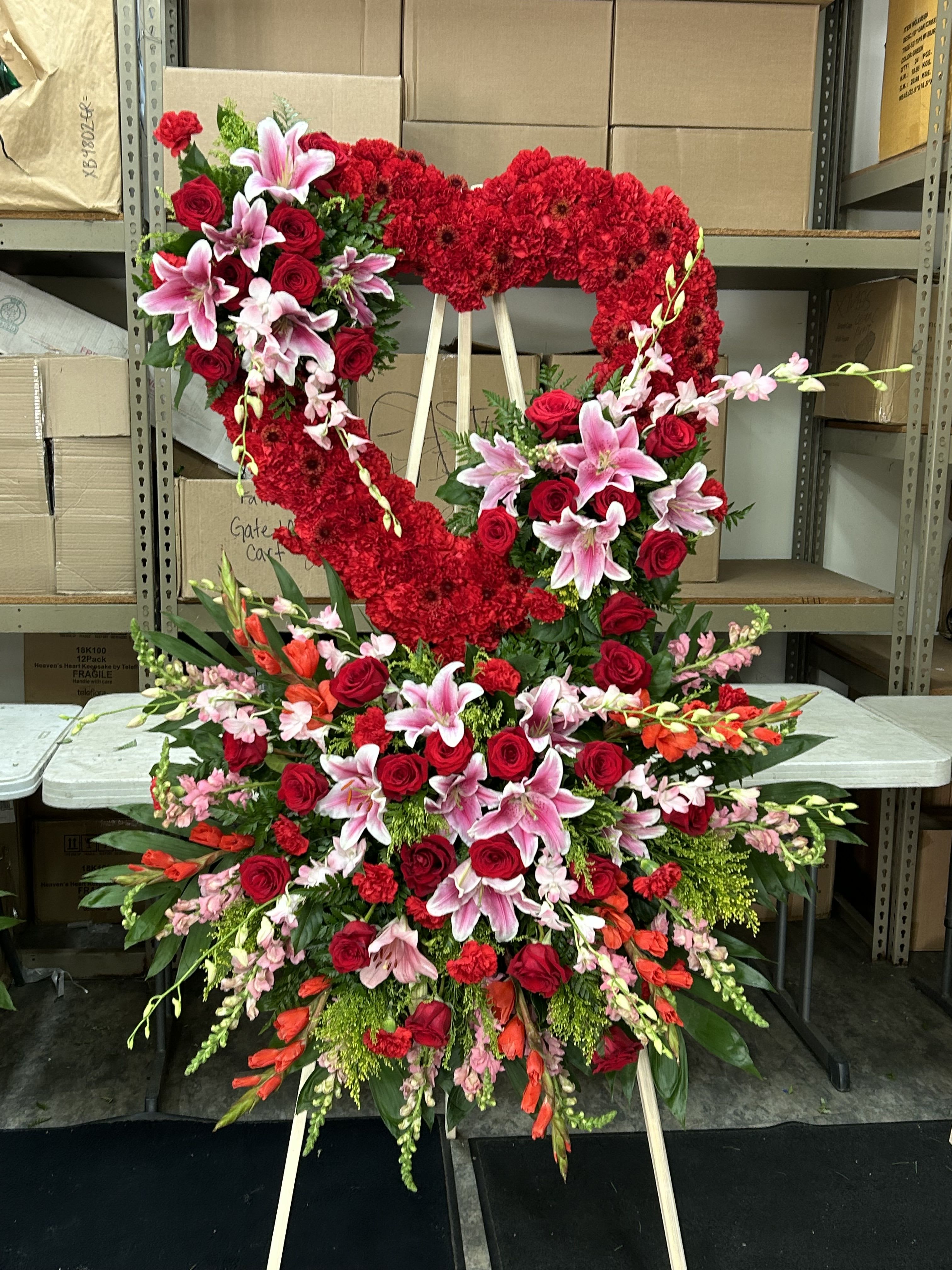 Large heart-shaped floral standing spray with red roses and pink lilies