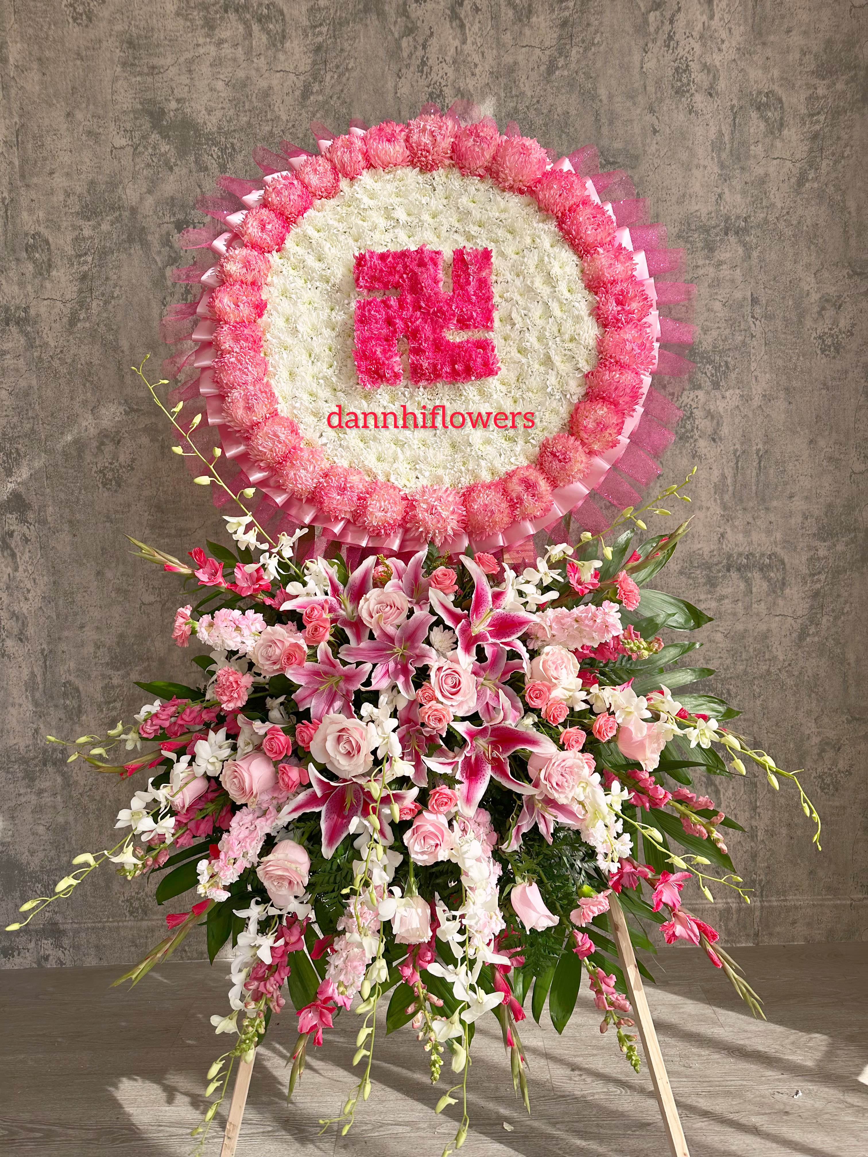 Pink and white funeral standing spray with a circular floral tribute above it
