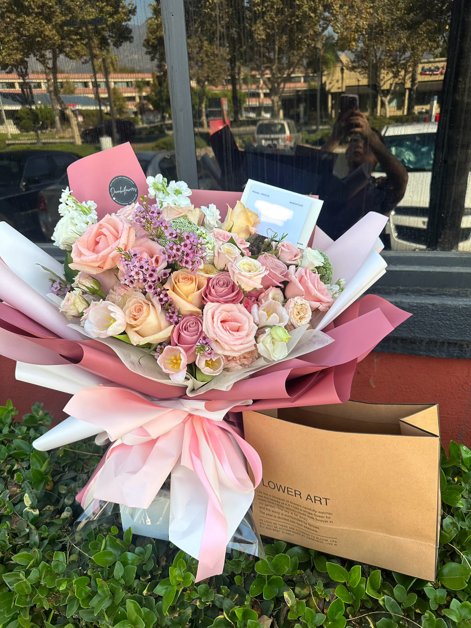 Pink and cream rose bouquet wrapped in pink paper with a ribbon