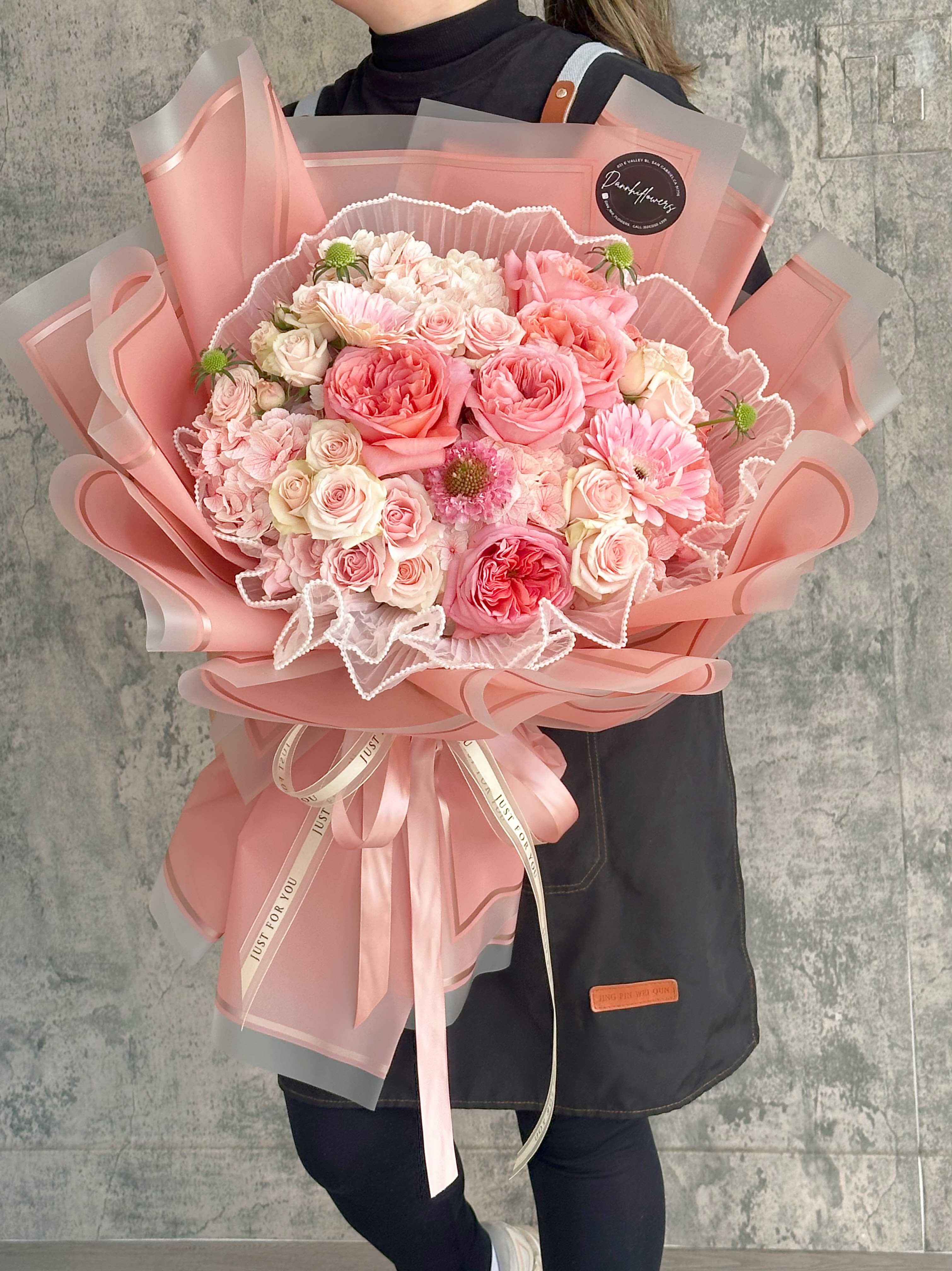 Large pink bouquet of roses and daisies wrapped in pink paper