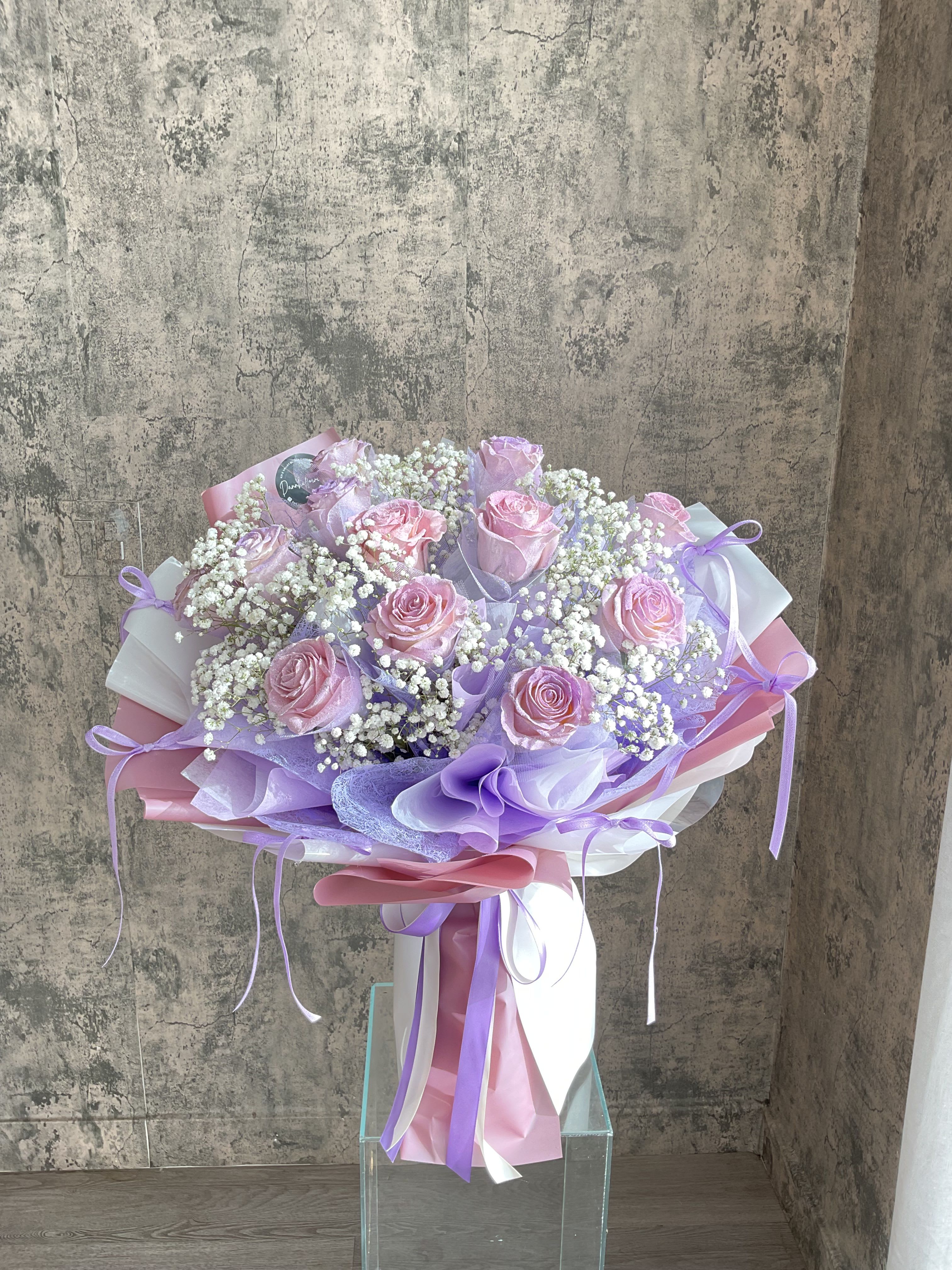 Bouquet of pink roses with white baby's breath and lavender wrapping
