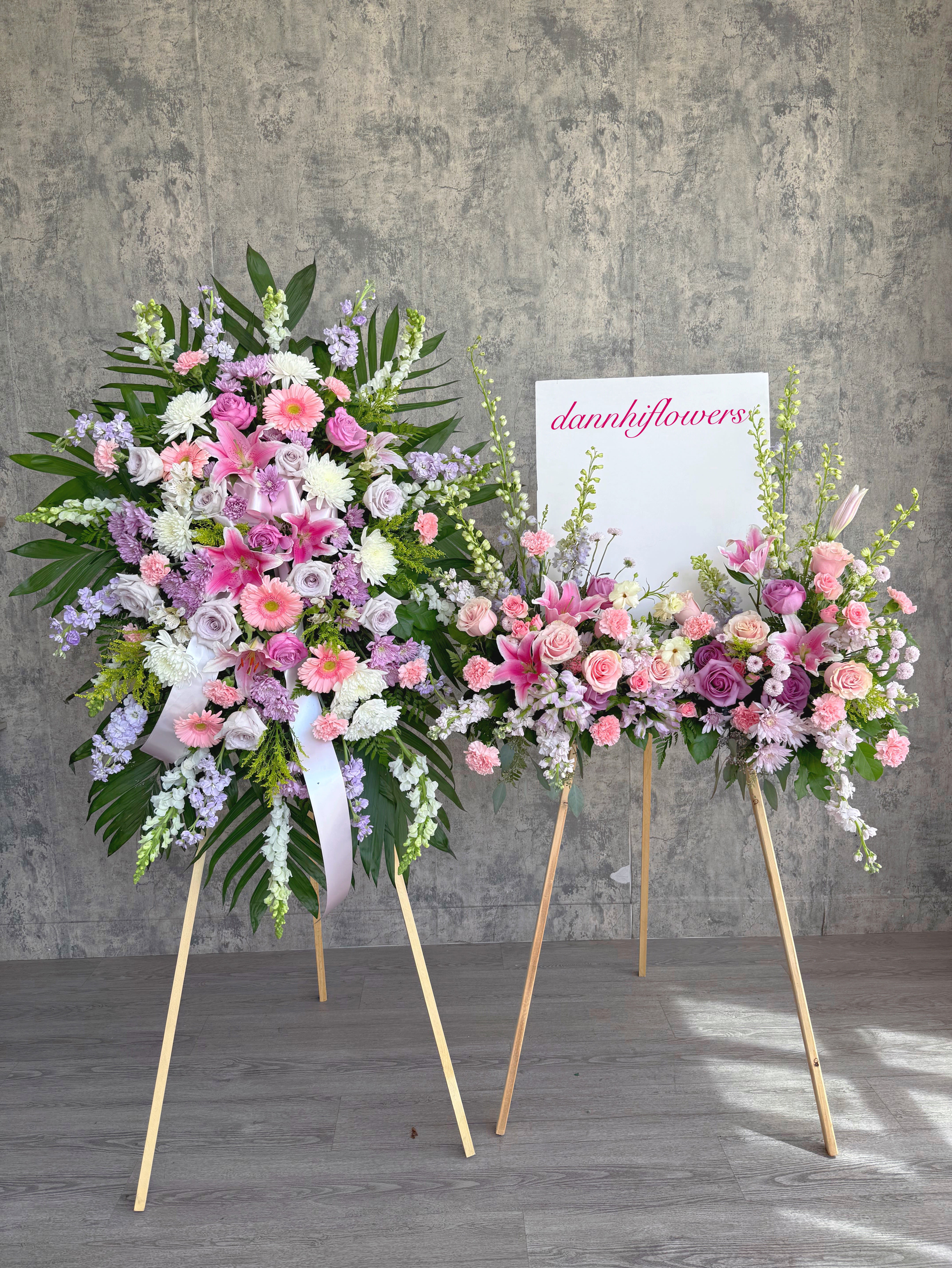 Two pastel floral standing sprays on easels with pink and lavender blooms