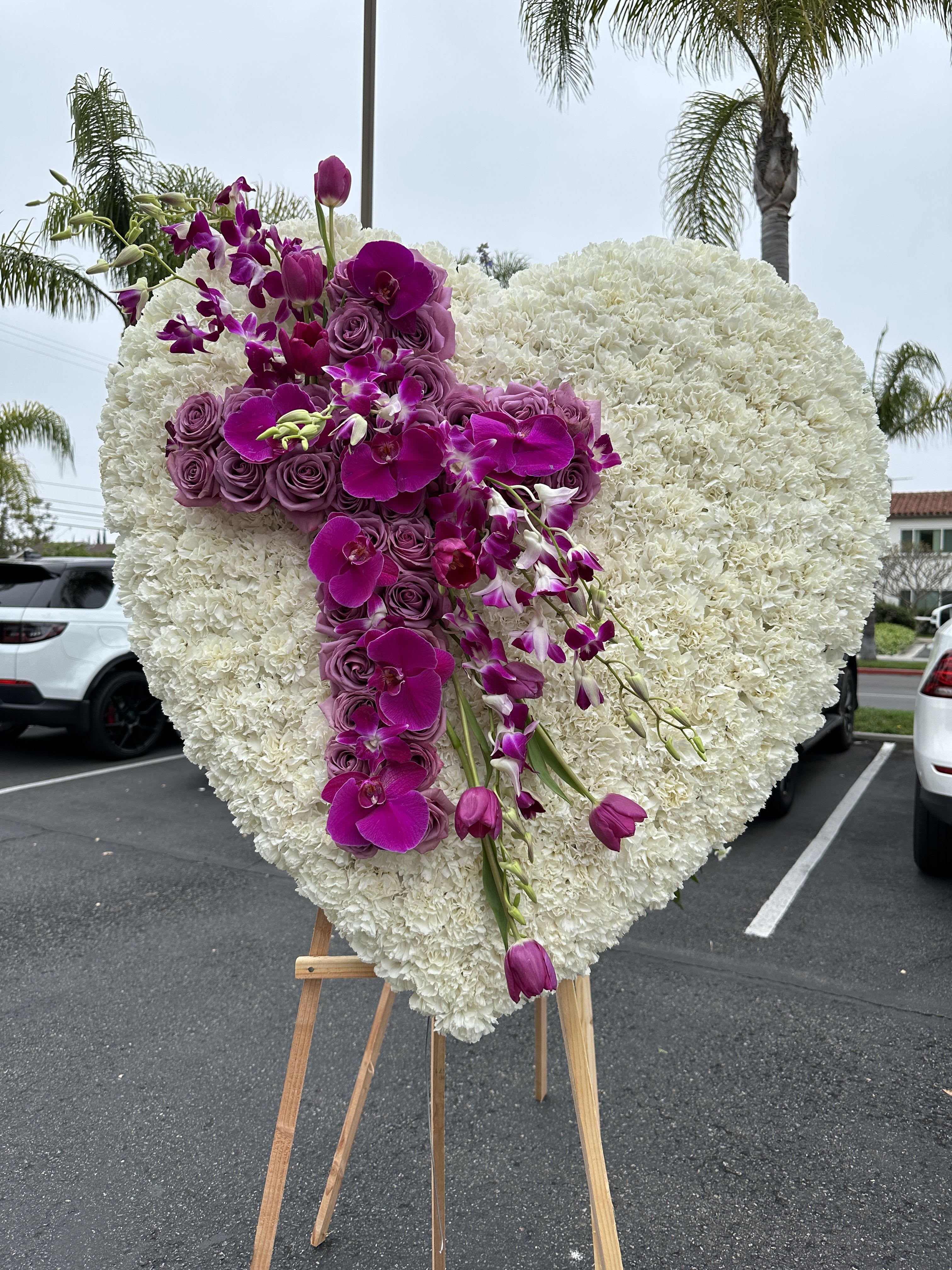 Heart-shaped white floral spray with purple orchids and roses