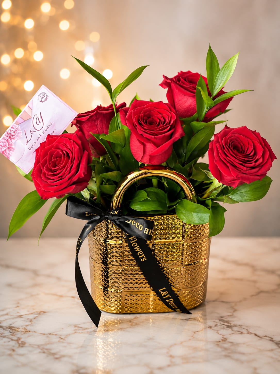 Red roses arranged in a gold basket with a black ribbon