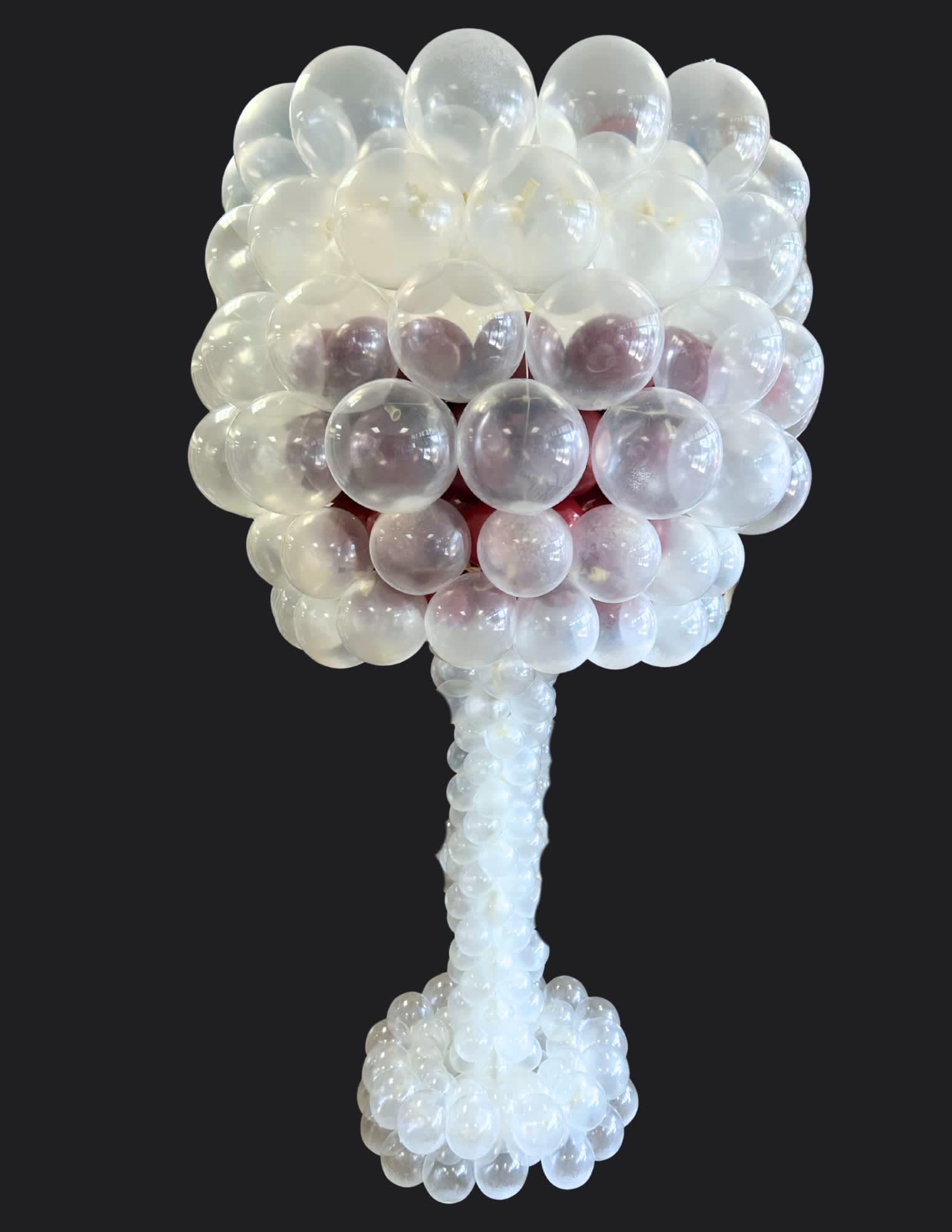 Clear balloon sculpture shaped like a tree on a black background