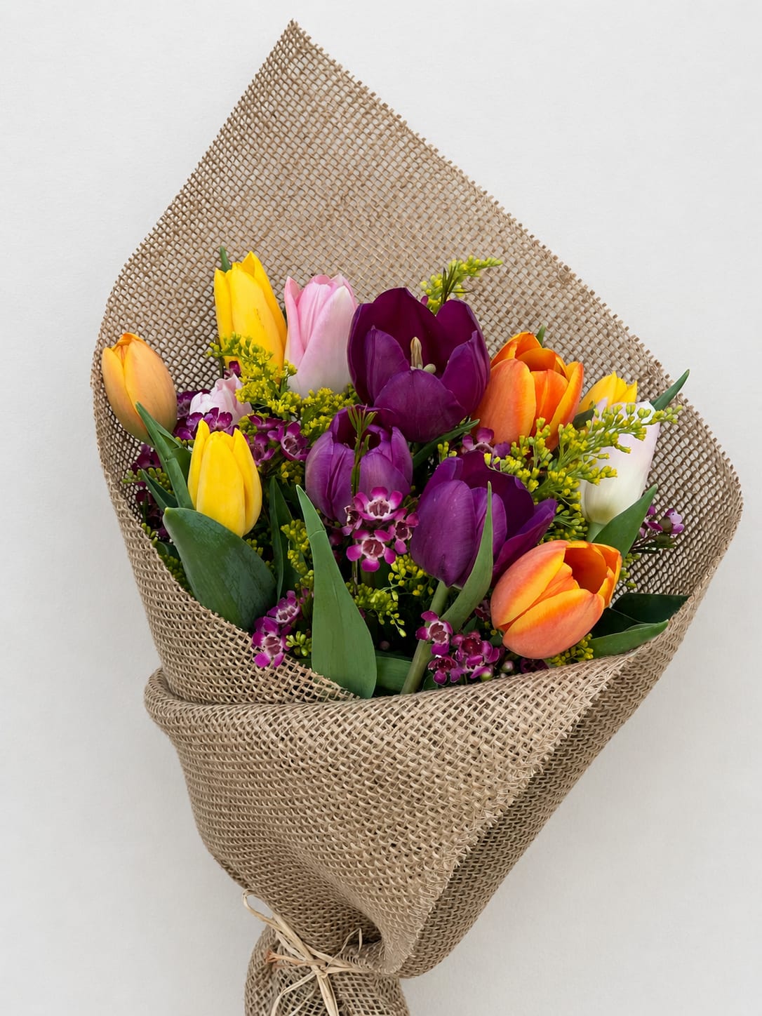 Bouquet of multicolored tulips wrapped in burlap