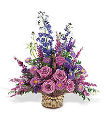 Pink roses and purple flowers arranged in a wicker basket