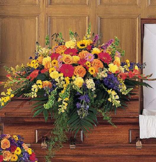 Large colorful flower spray on a wooden casket