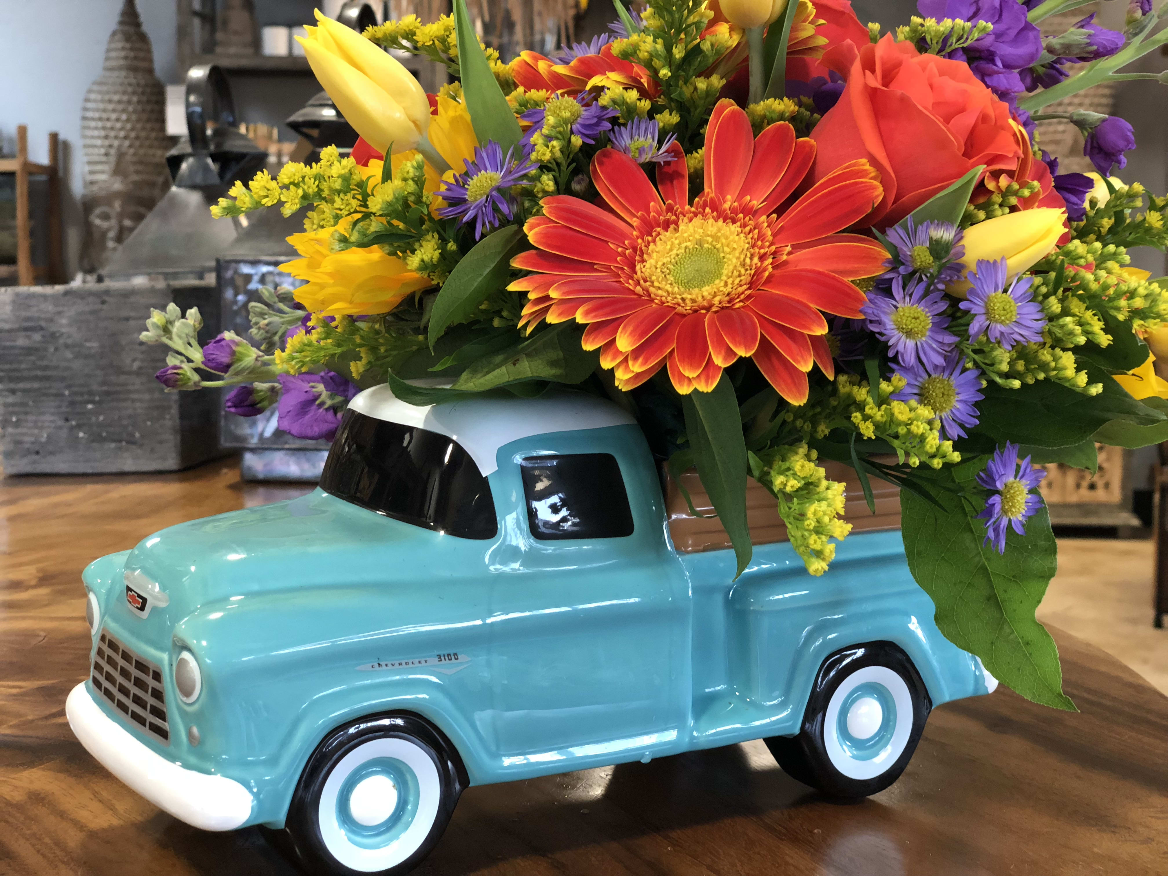 Colorful flower arrangement in a turquoise ceramic truck container