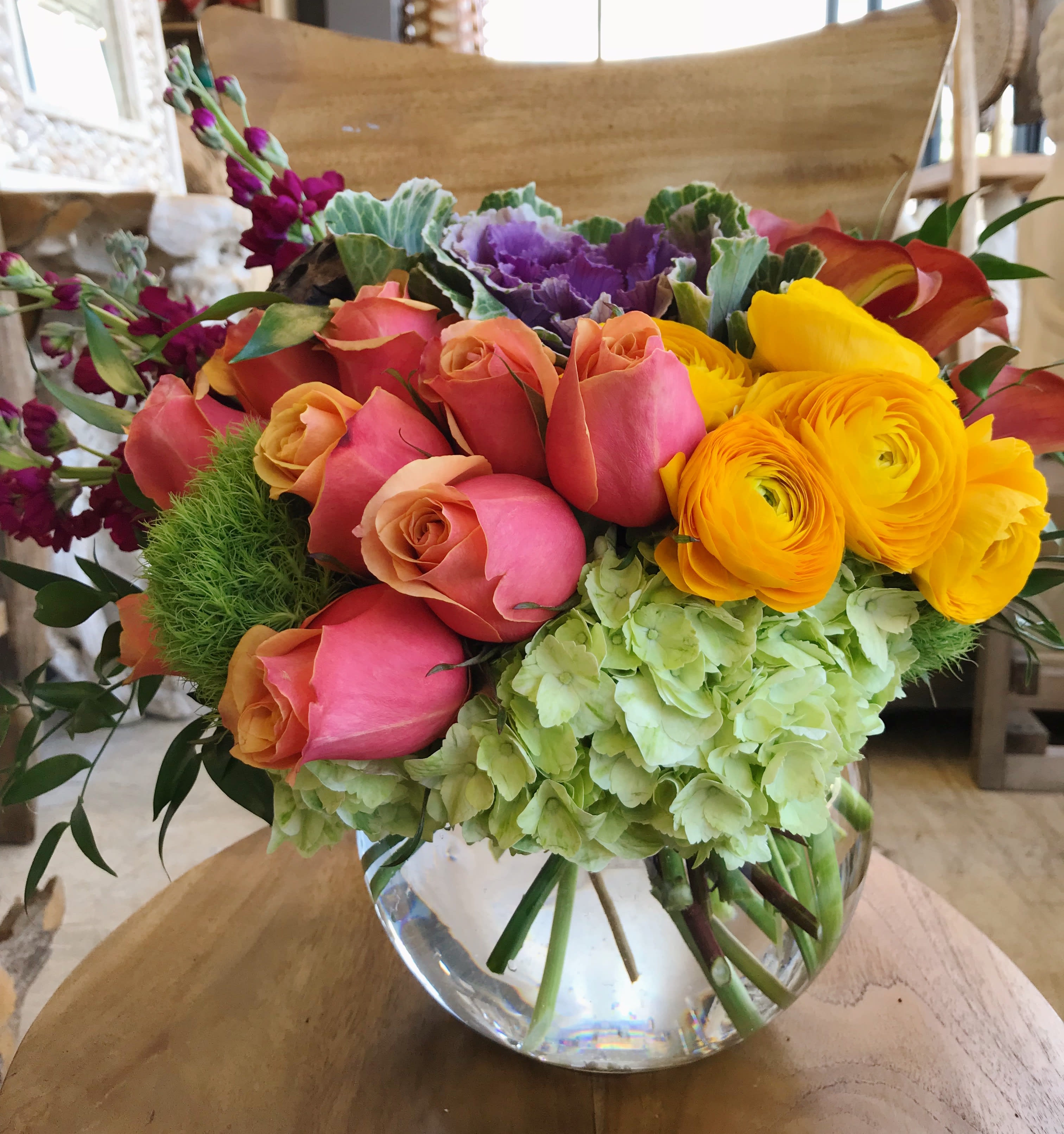 Mixed bouquet of roses, ranunculus, hydrangea, and calla lilies in a glass vase