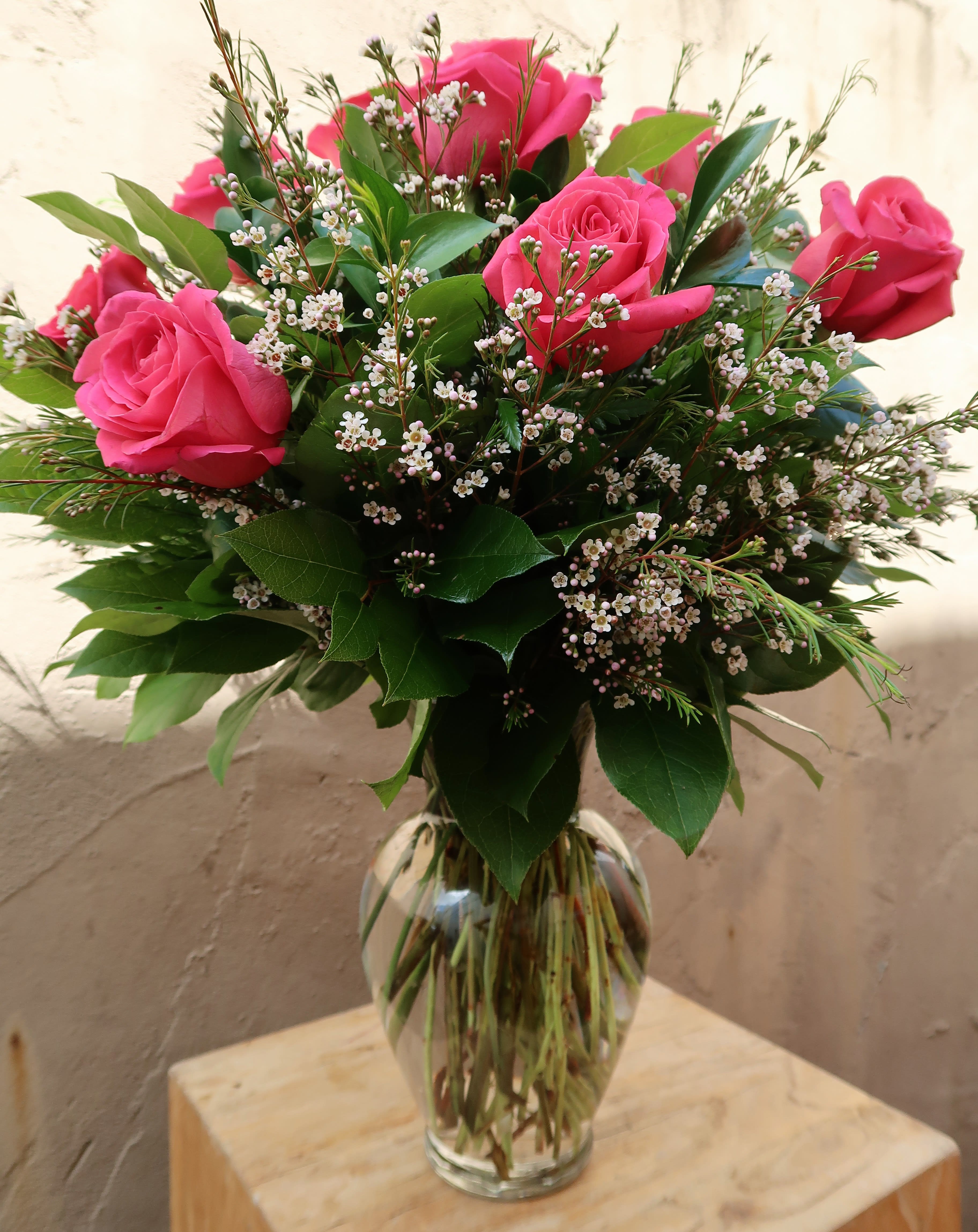 Pink roses arranged in a clear glass vase with small white filler flowers