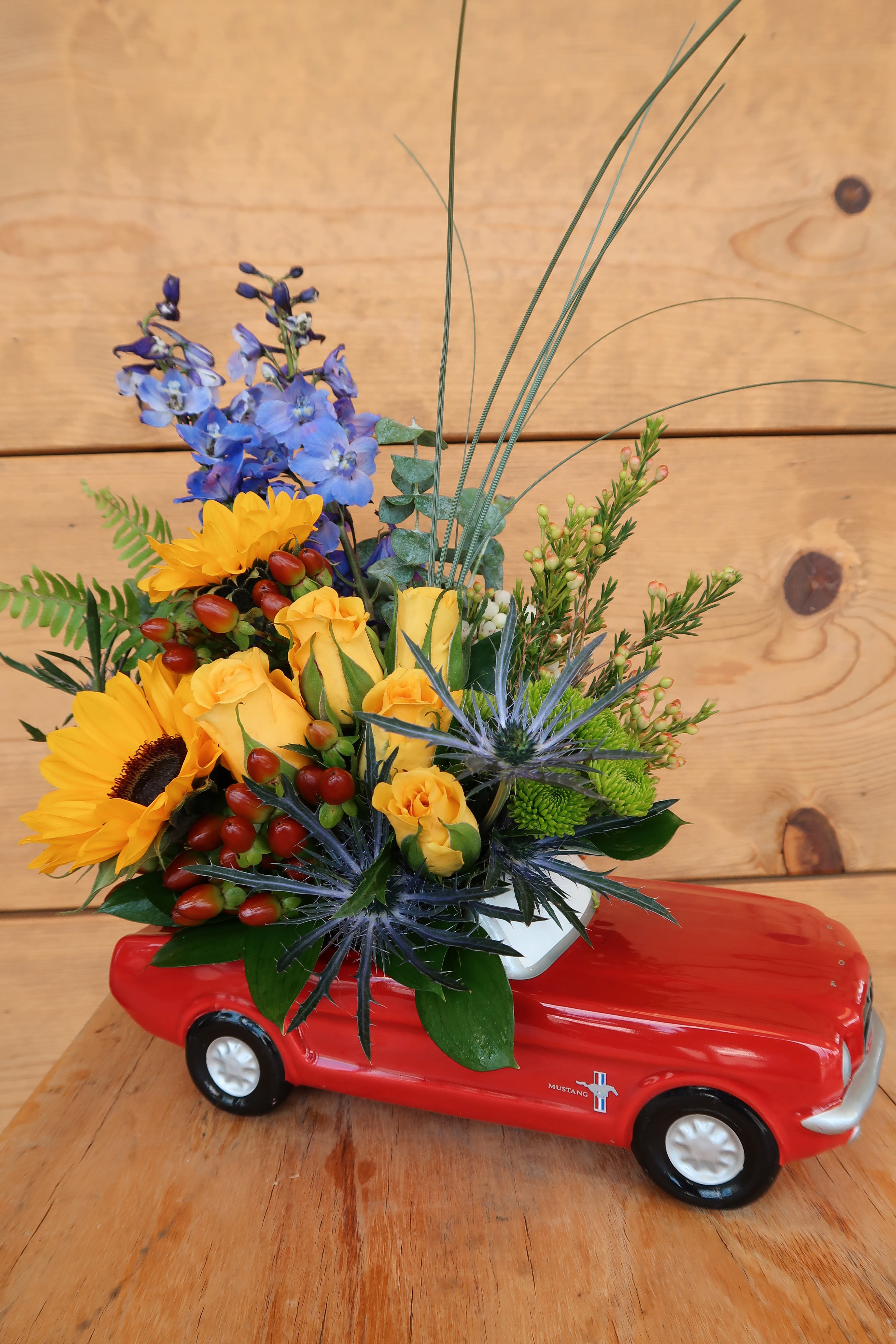 Mixed flower arrangement in a red toy car container
