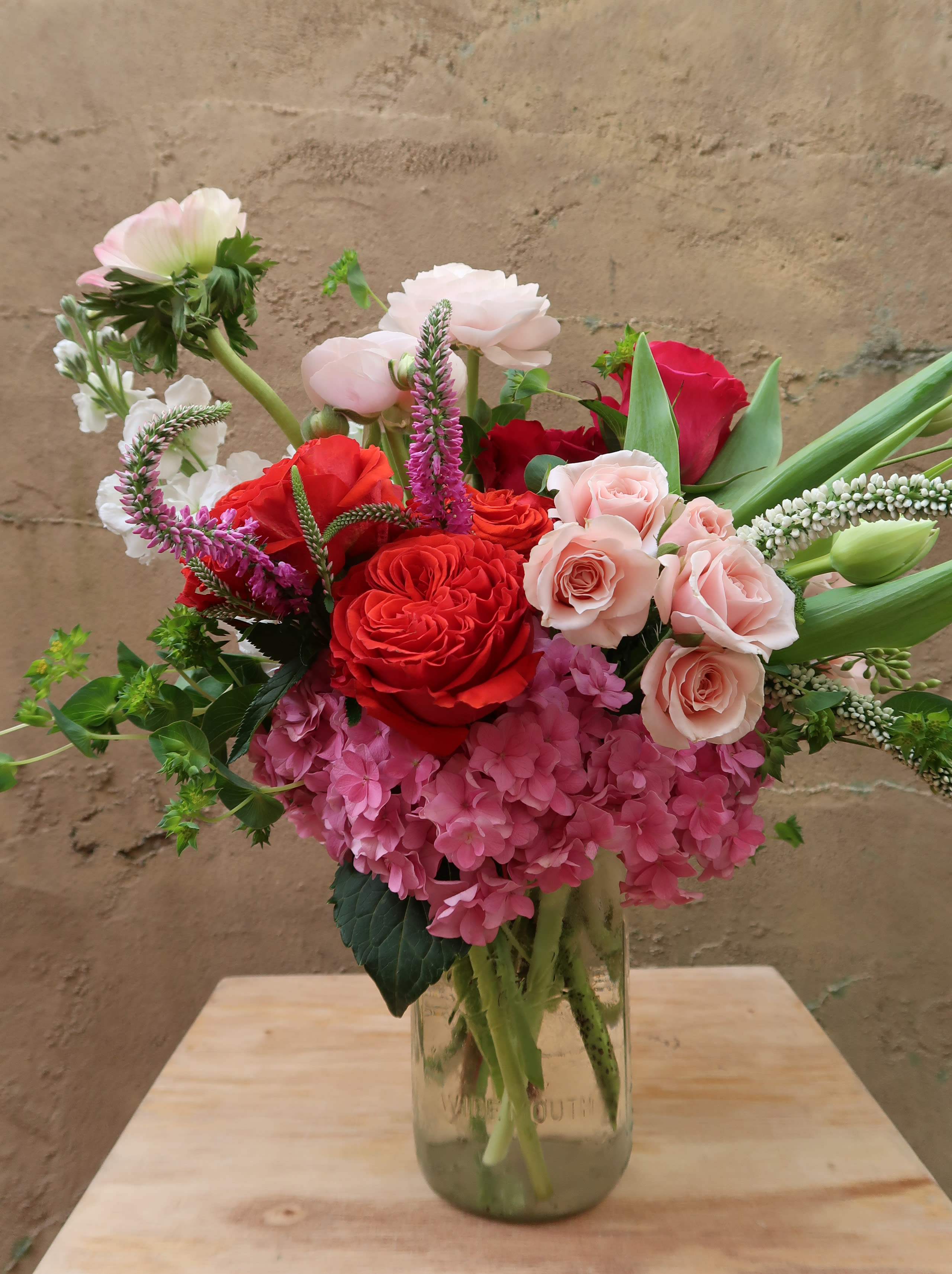 Mixed bouquet of red, pink, and white flowers in a glass vase