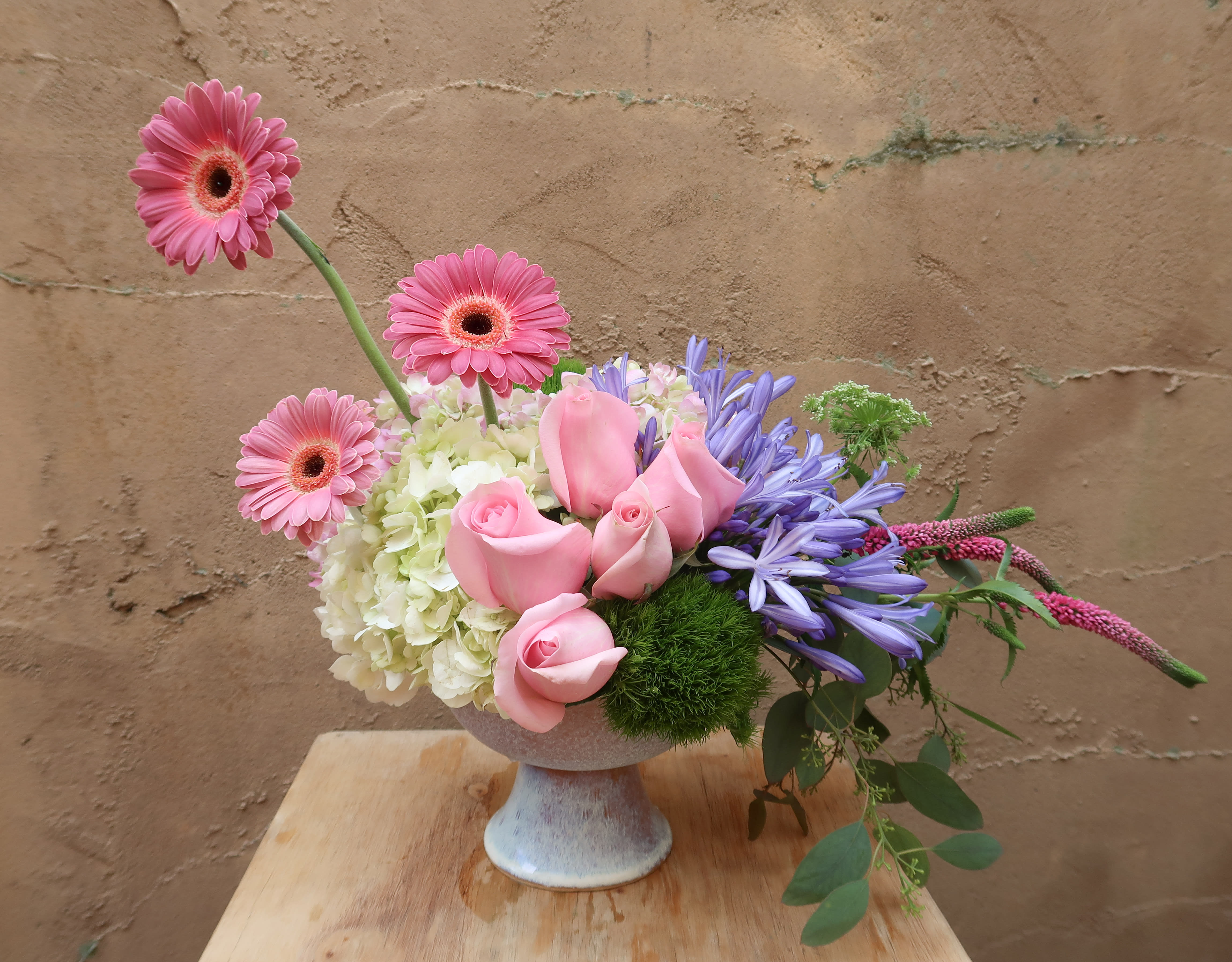 Pink roses and gerbera daisies in a pedestal vase