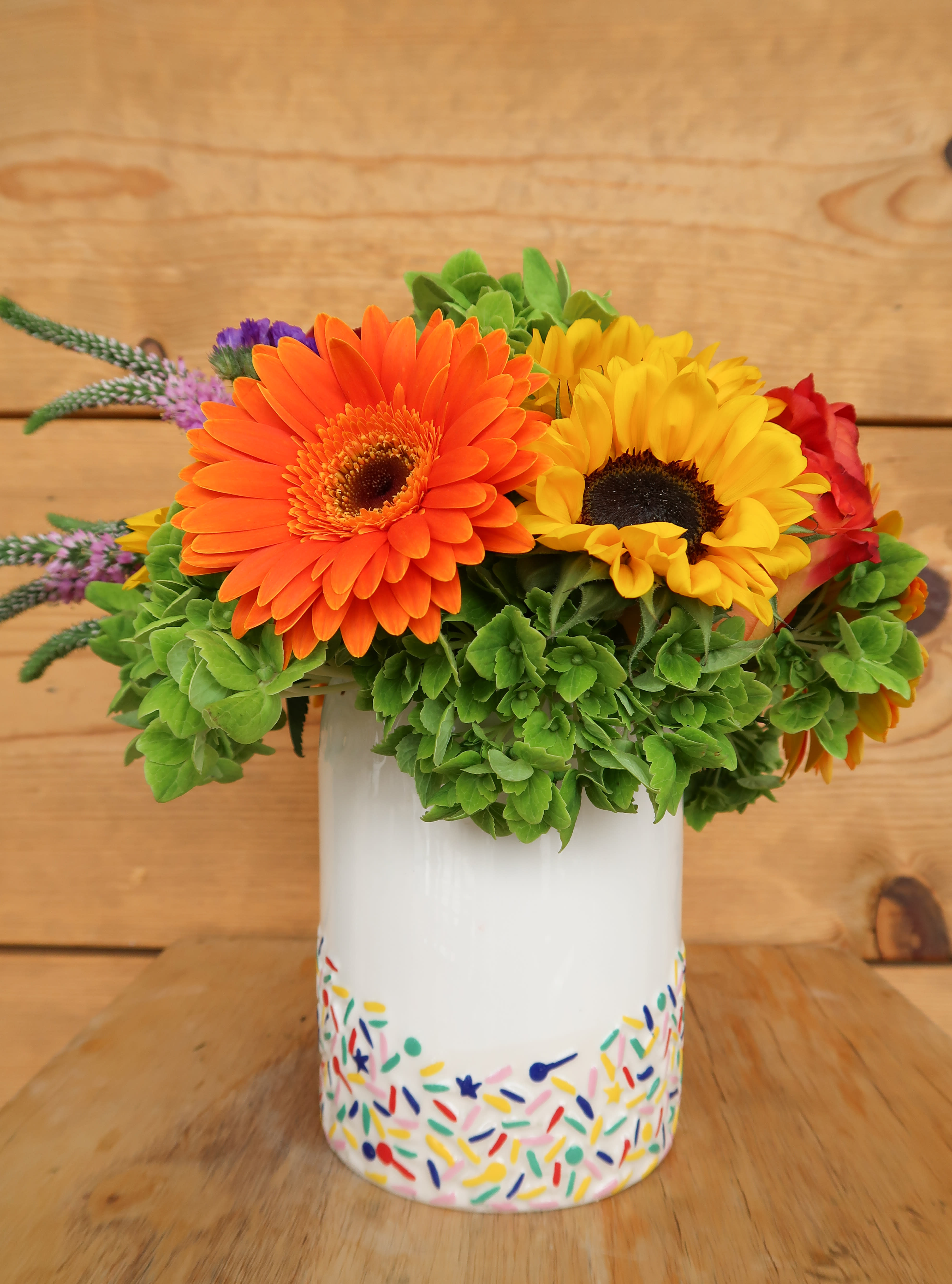 Bright gerbera daisies in a painted white vase