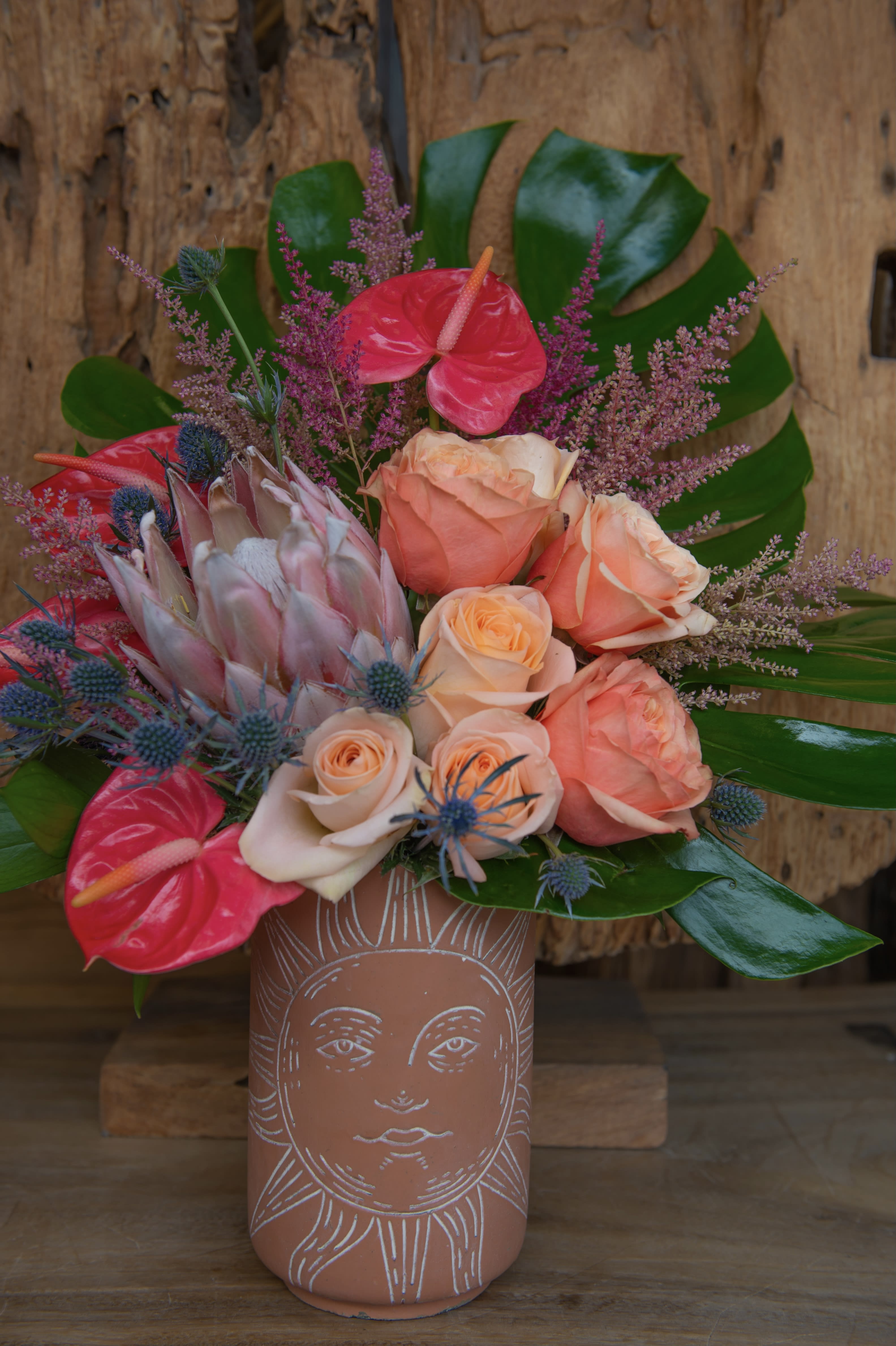 Bouquet of peach roses and pink anthuriums in a terracotta vase