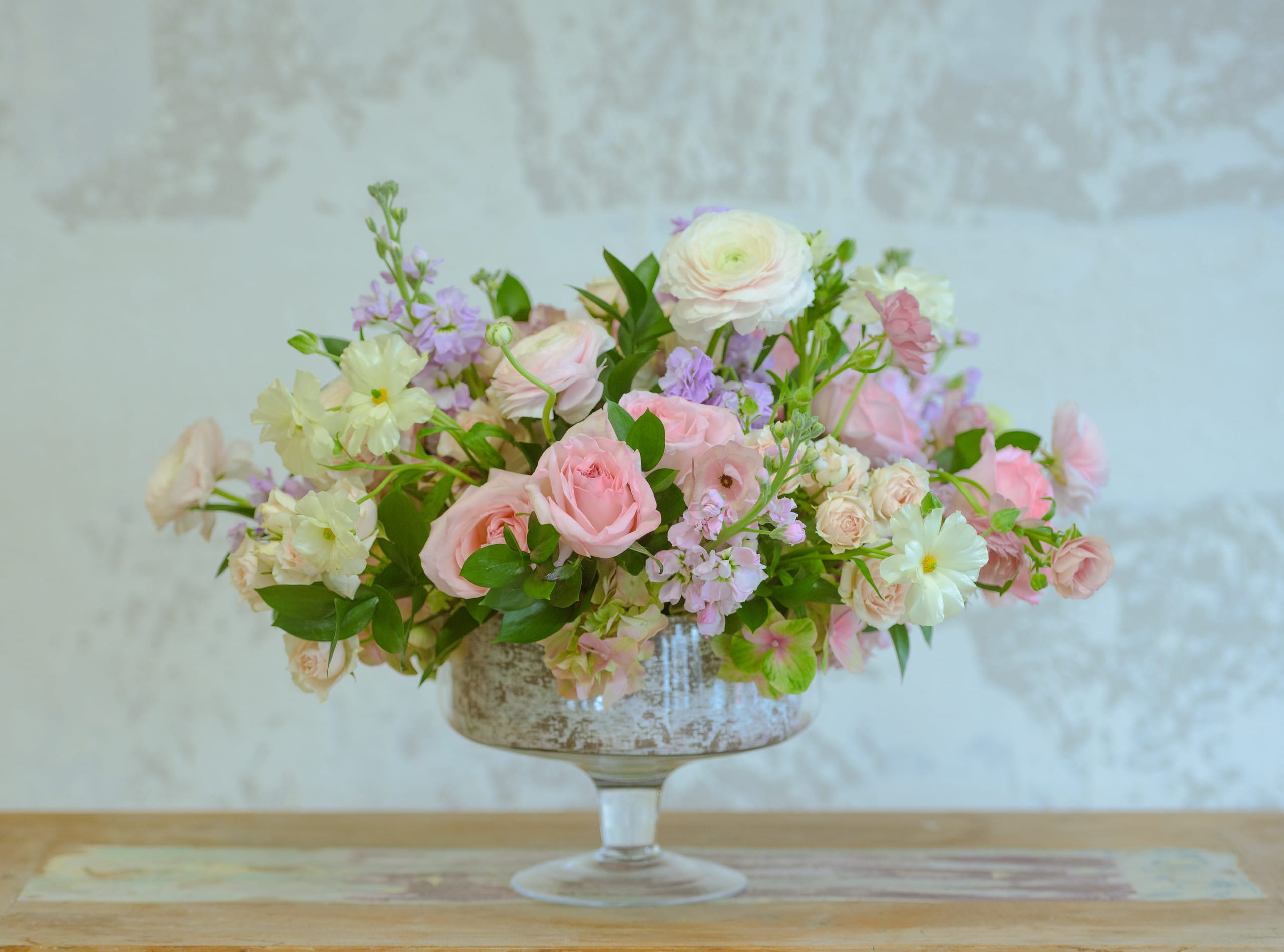 Pink and white floral arrangement in a glass compote vase