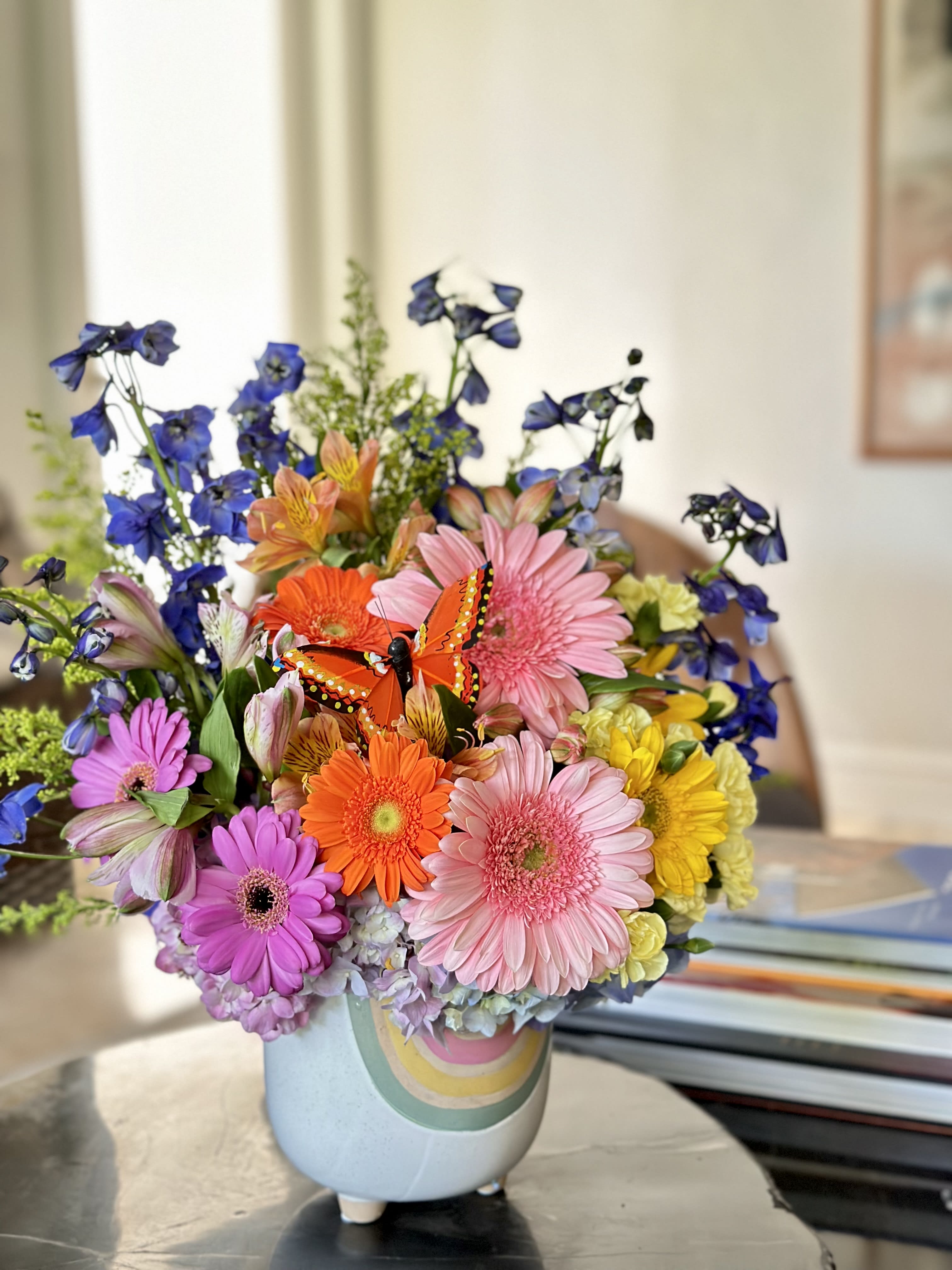 Colorful mixed bouquet in a pastel vase with a butterfly decoration