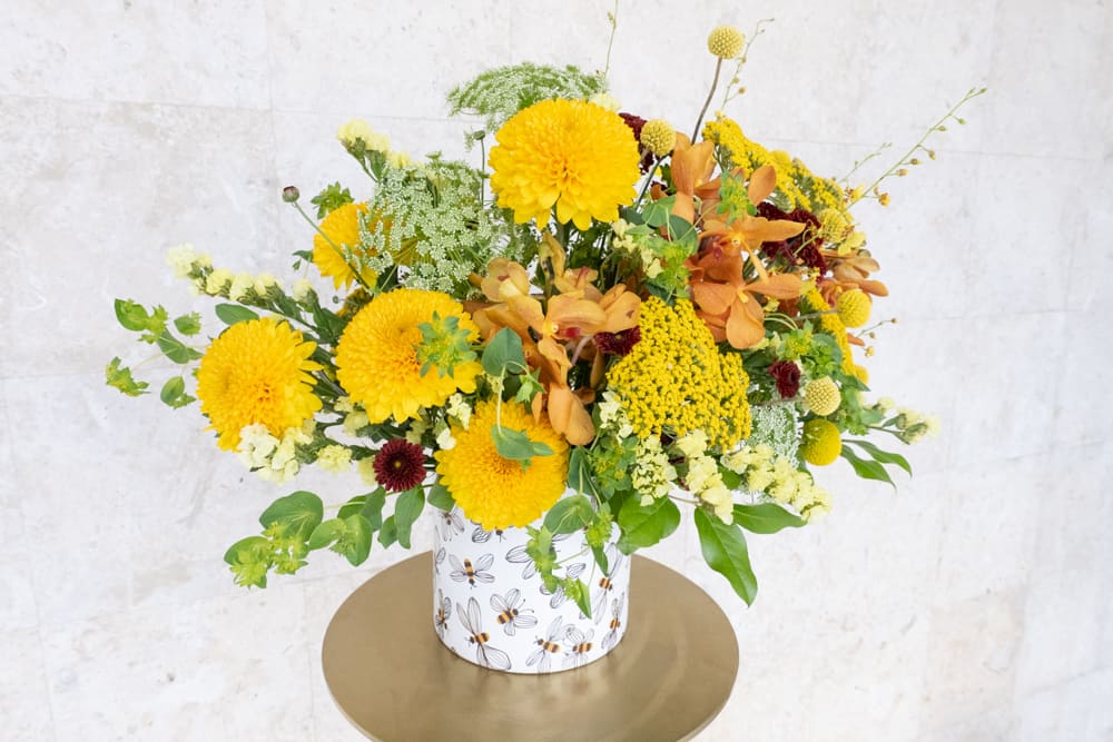 Yellow and orange floral arrangement in a patterned container
