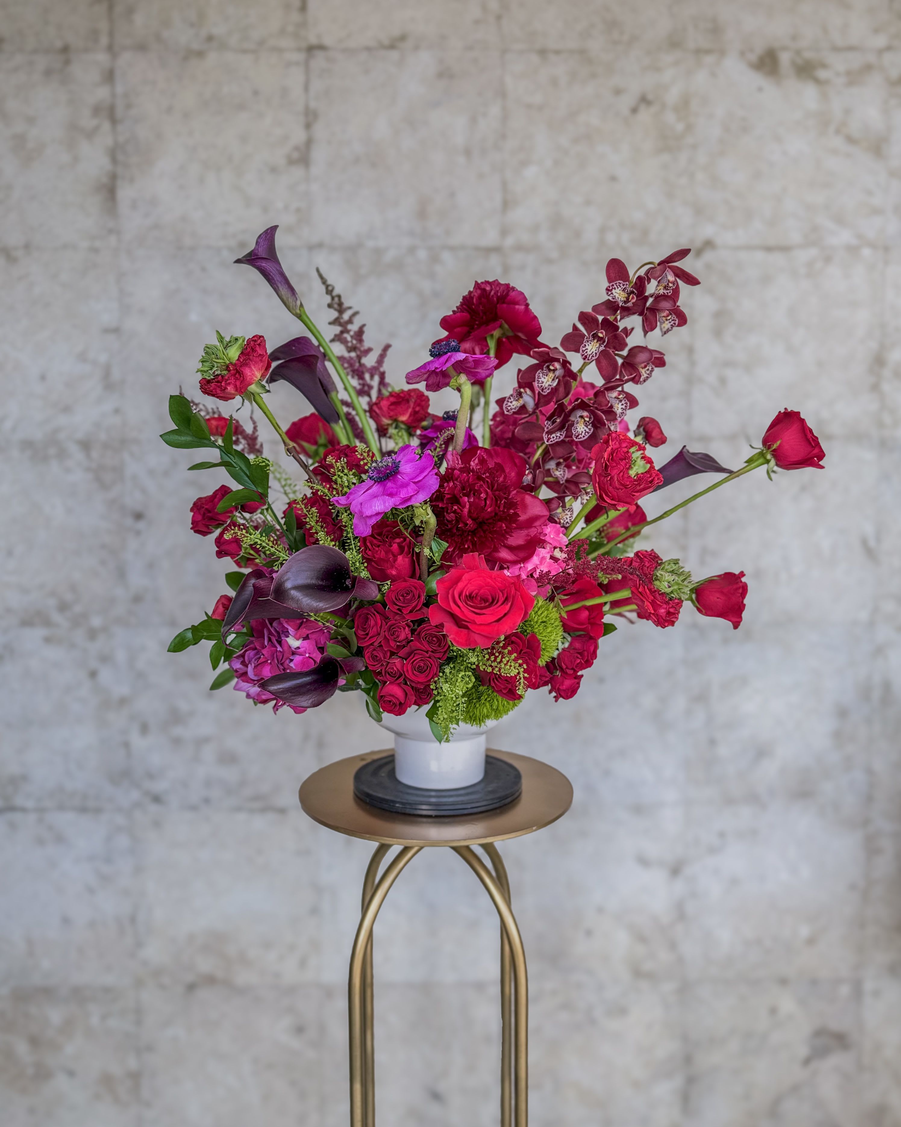 Bright pink and purple floral arrangement in a white vase